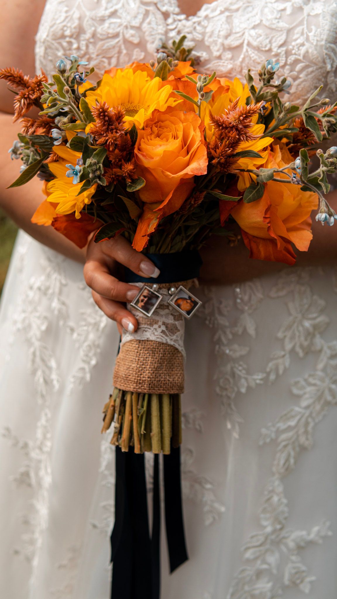 A vibrant orange and yellow bridal bouquet wrapped in burlap against a white wedding dress.