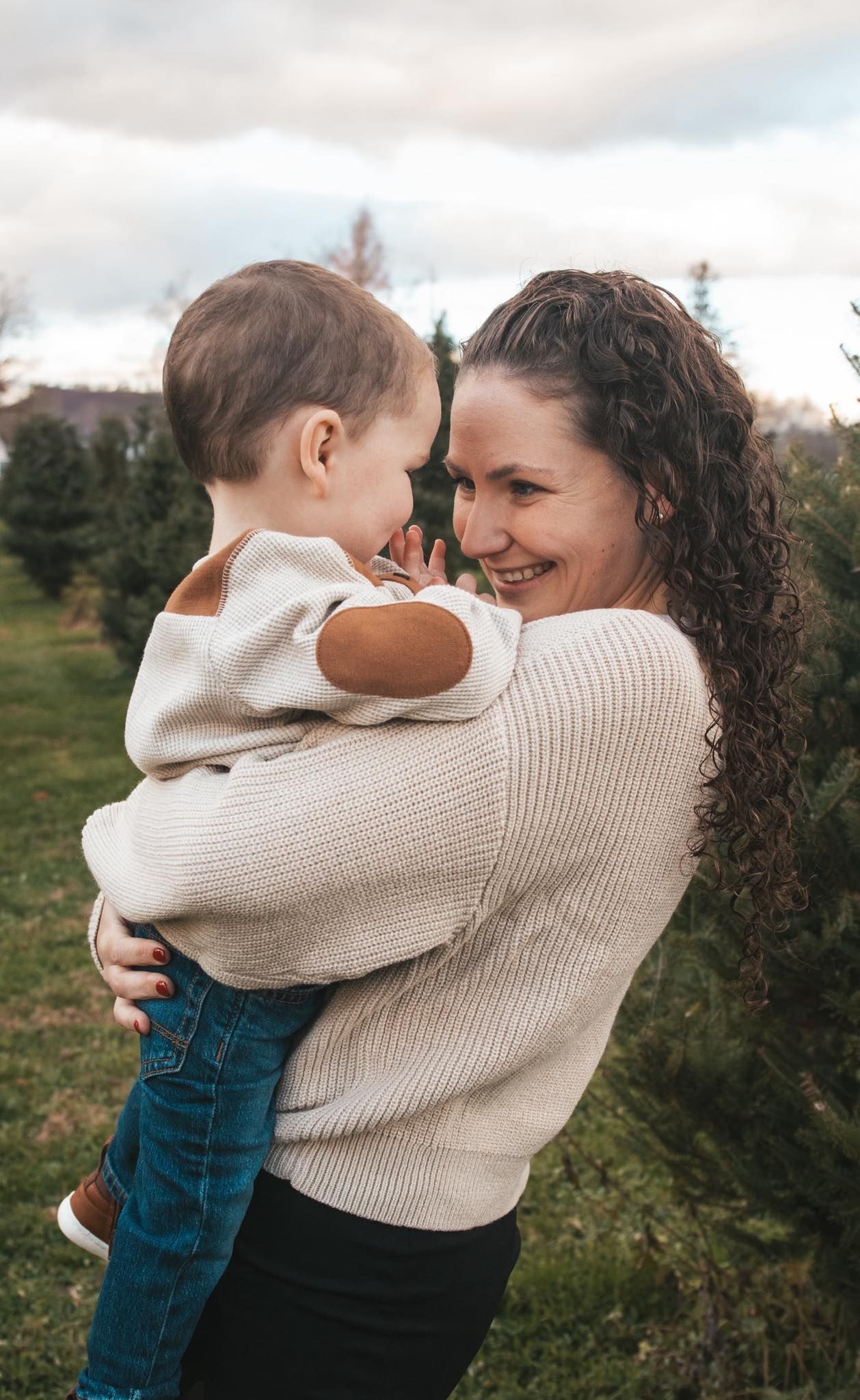Sweet candid moments captured outdoors in a natural setting with warm sweaters.
