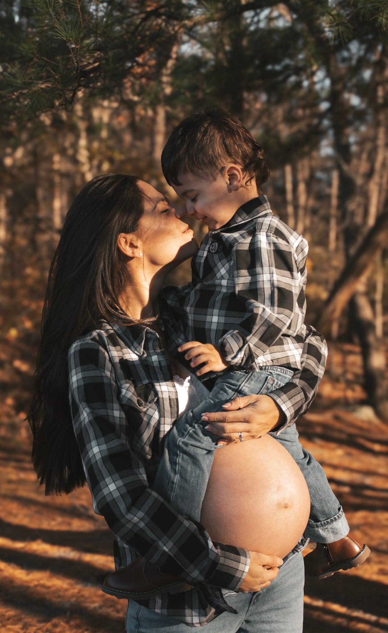 Maternity photo series shows couple embracing in forest during golden hour sunset.