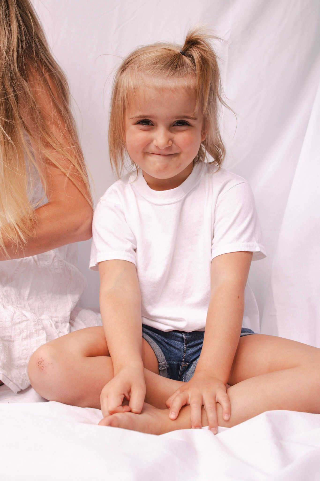 A child in a white t-shirt poses against a white backdrop in a series of casual studio portraits.