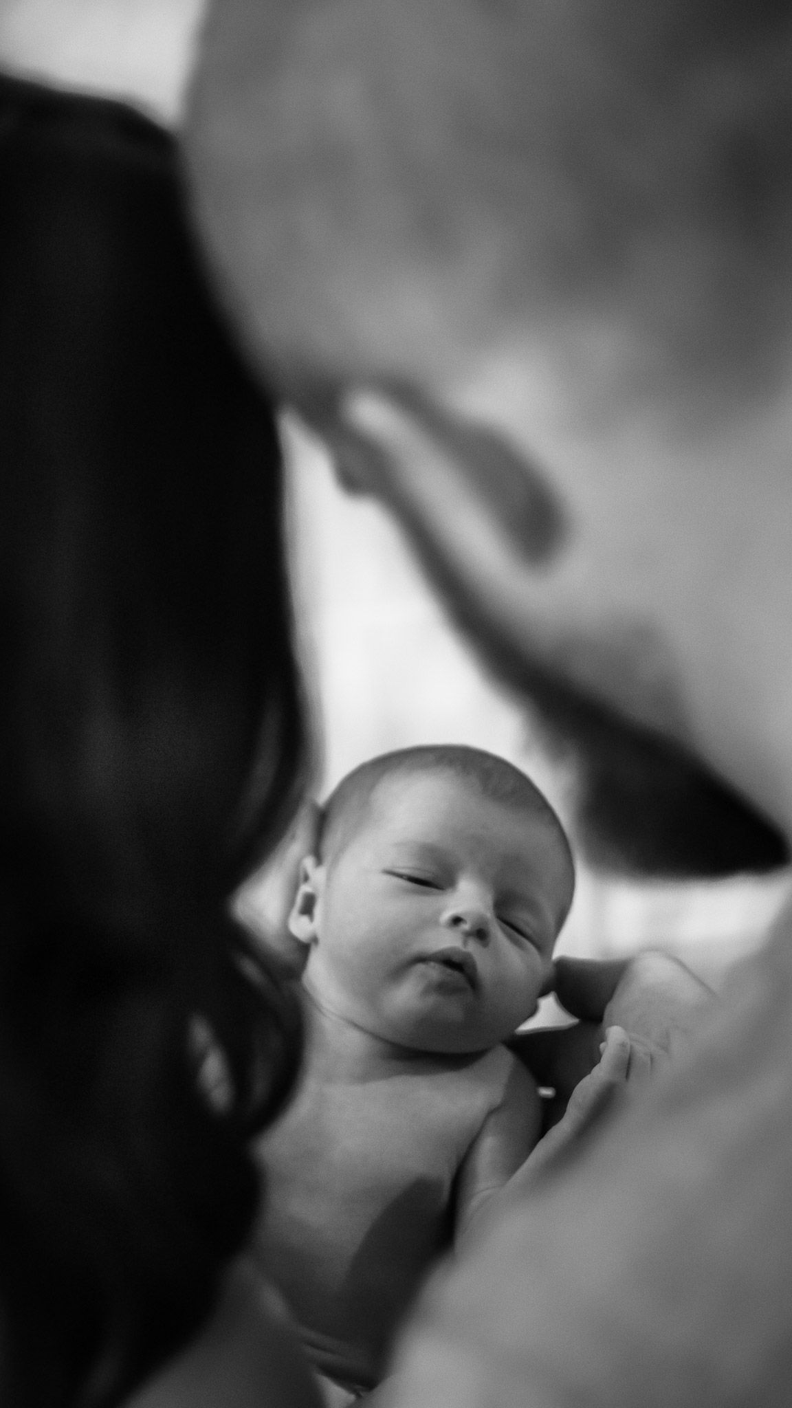 Black and white intimate portrait of sleeping newborn in soft focus.