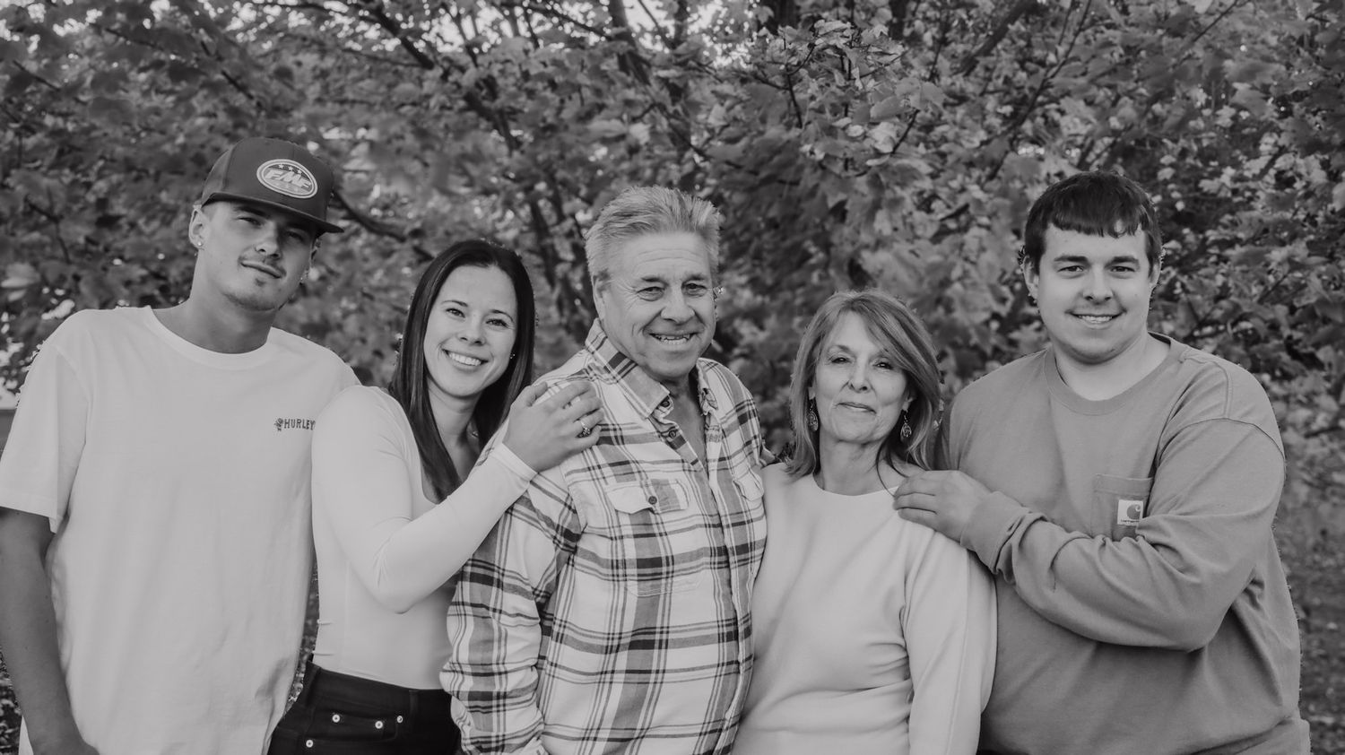 A collection of black and white family photographs arranged in a horizontal strip showing outdoor gatherings and group poses.