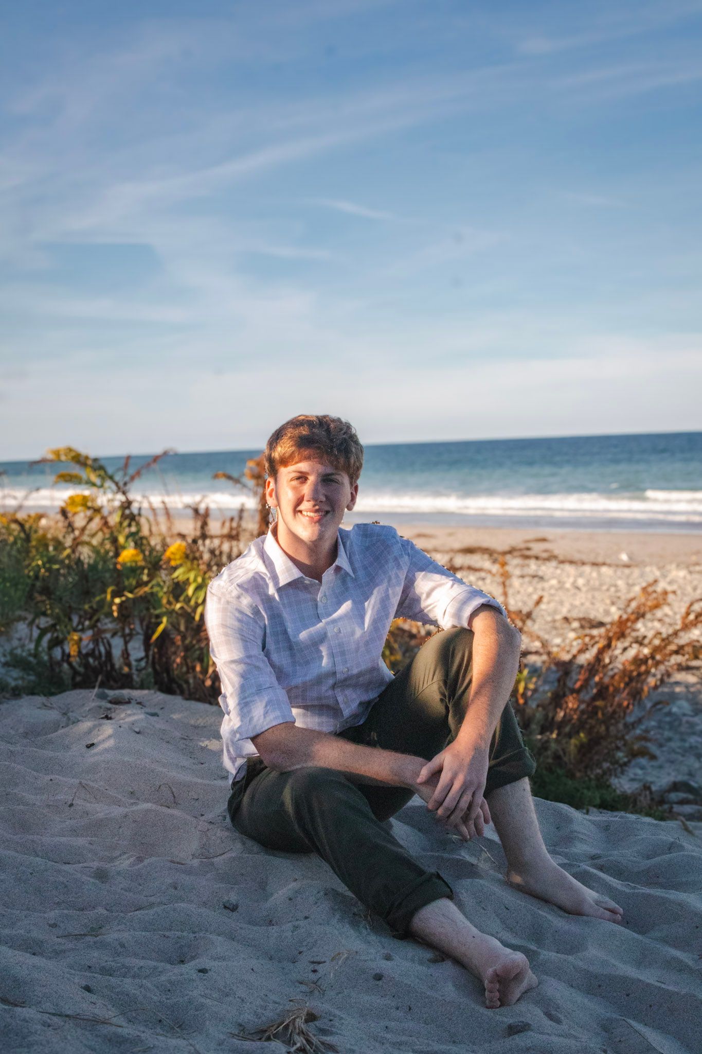 A relaxed beachgoer lounges on sandy shores with ocean waves and blue skies in the background.