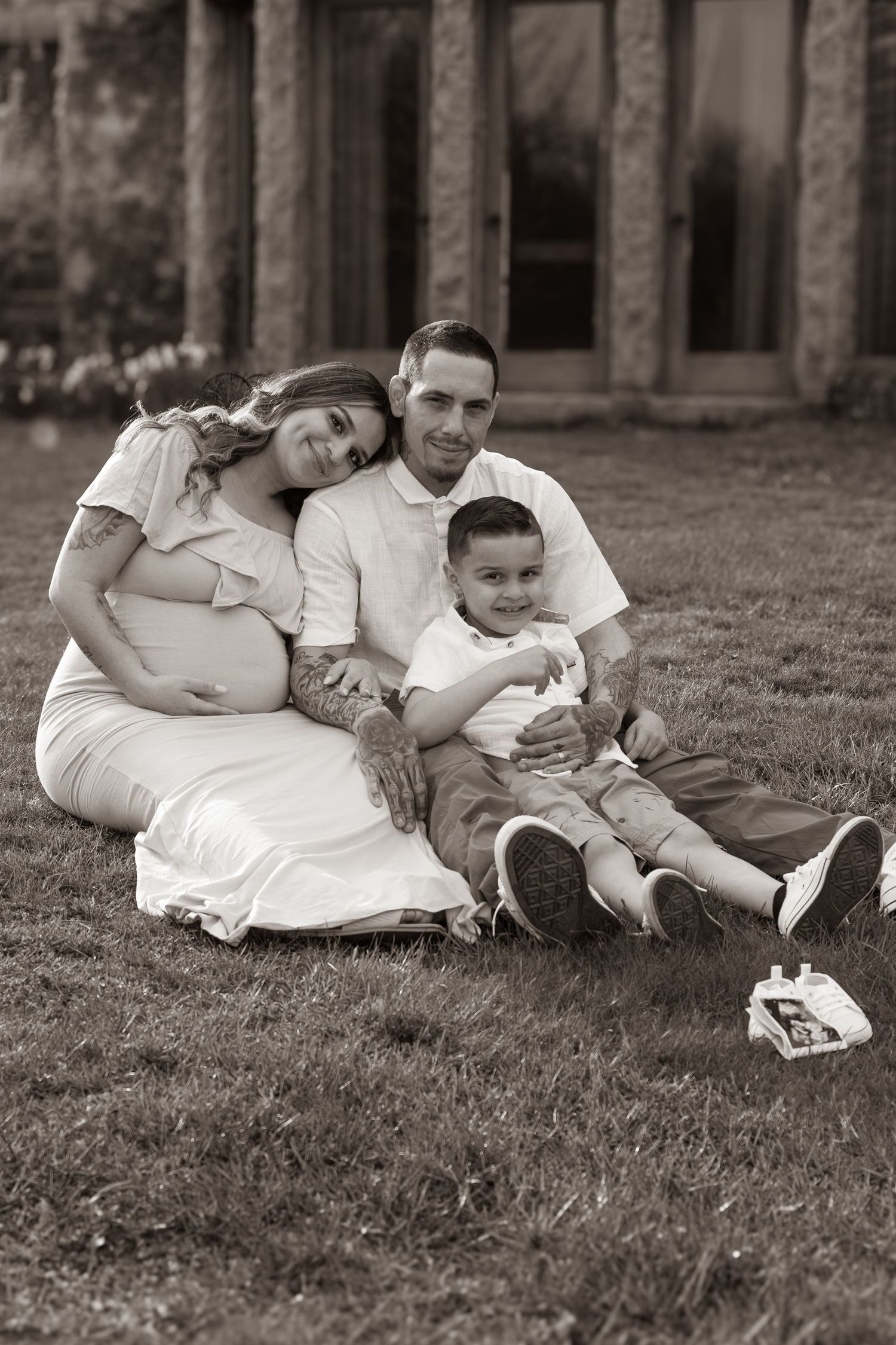 Black and white family maternity photos on grass showing intimate moments.