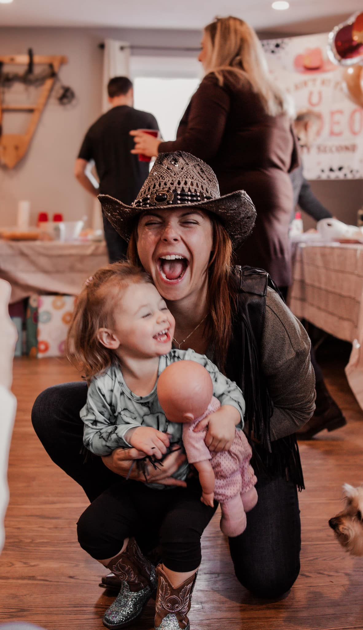 A joyful moment captured in a dance studio as parent and child share laughter and playful interaction on wooden floors.