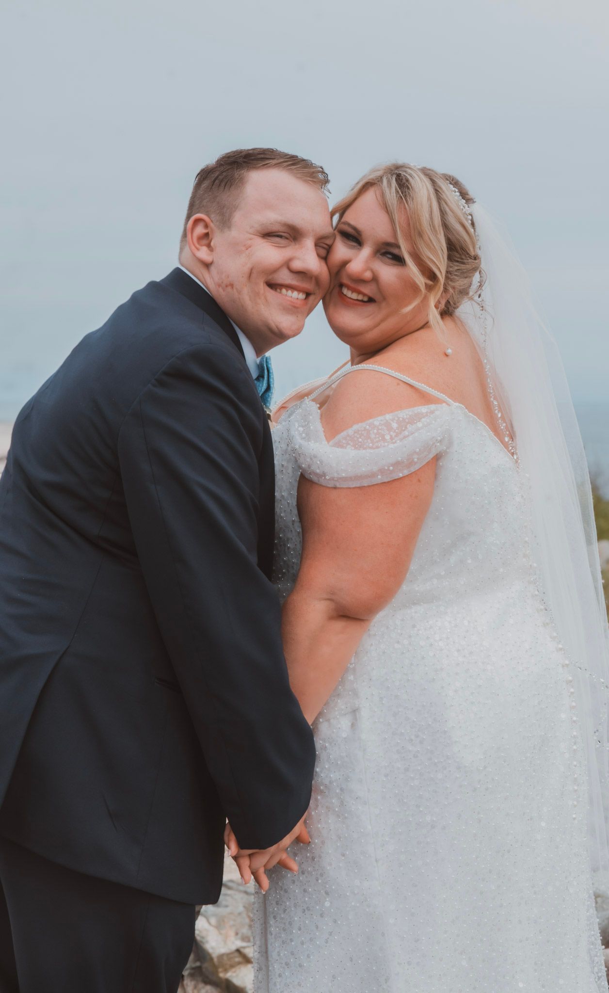 A couple shares joyful moments together in their wedding attire during an outdoor photoshoot.