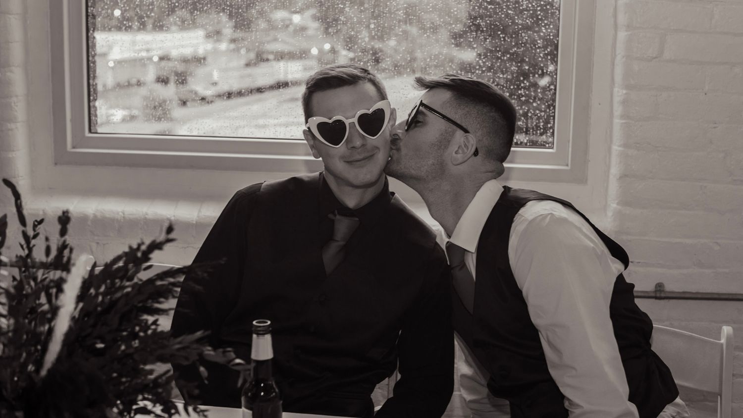 Black and white photo of guests enjoying themselves at an outdoor wedding celebration.