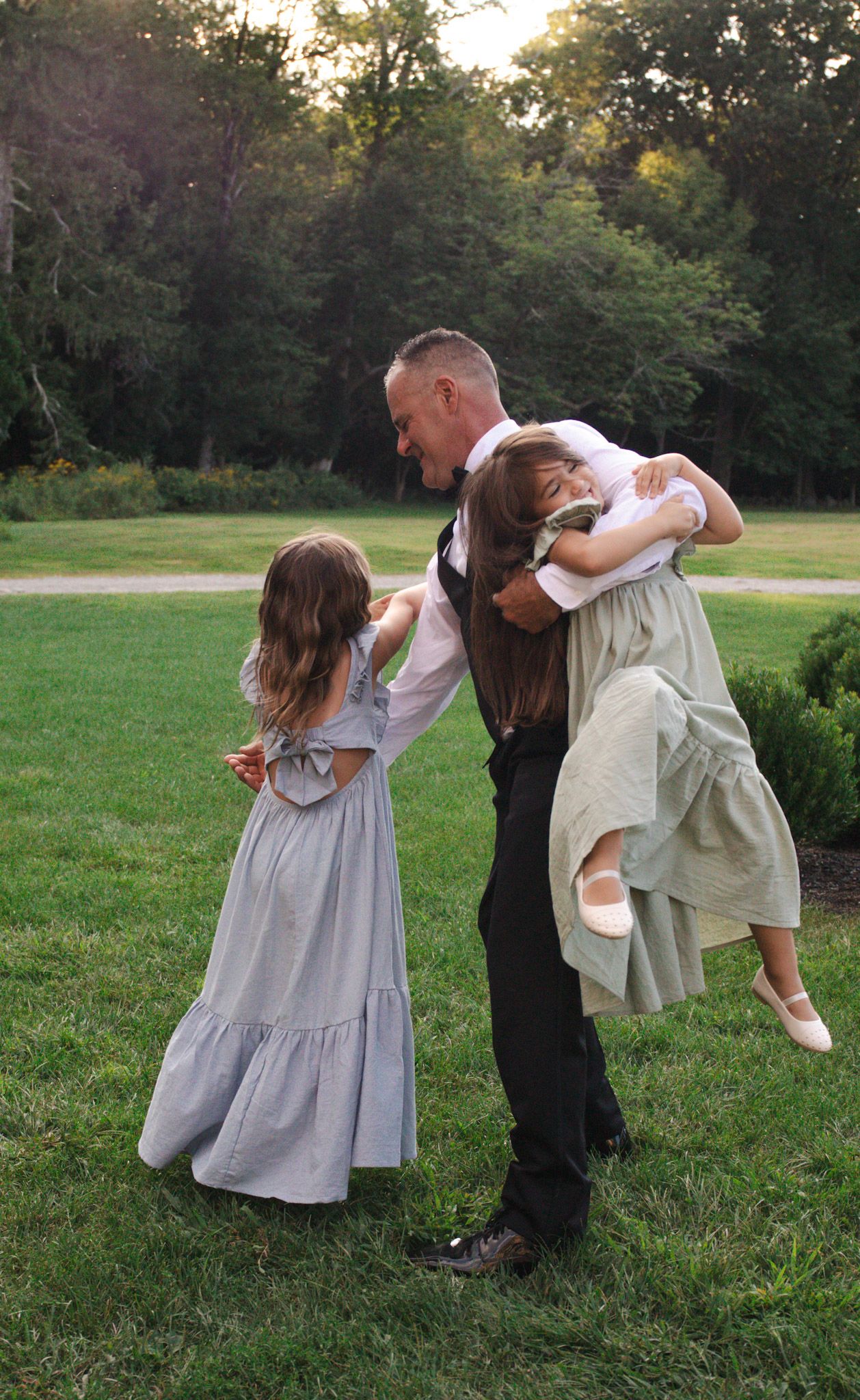 Dancing partners share playful dips and spins on a grassy field at sunset.