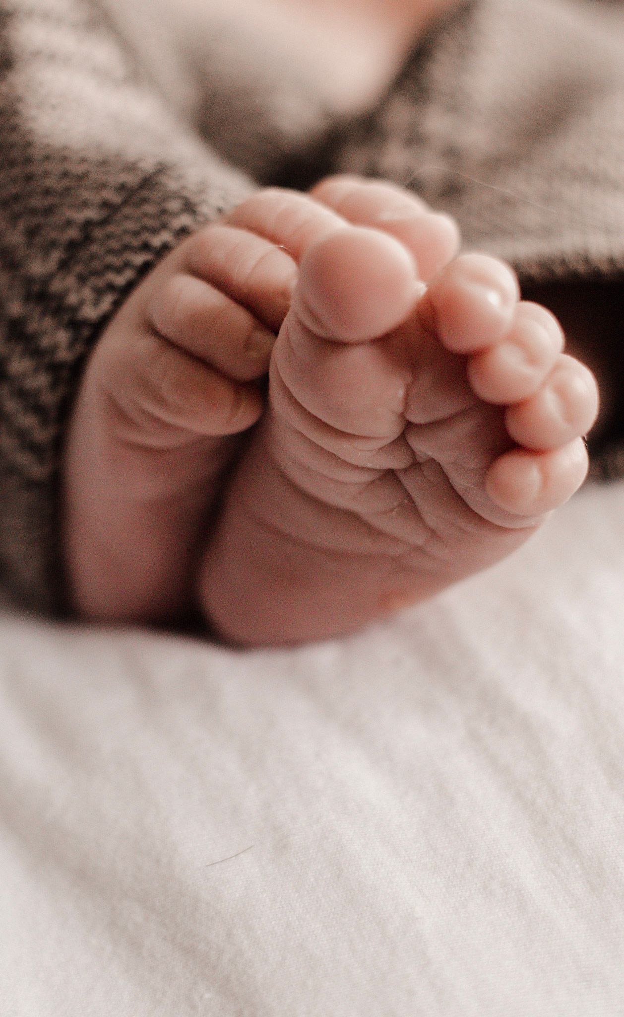 Close-up view of tiny newborn baby feet on white fabric.
