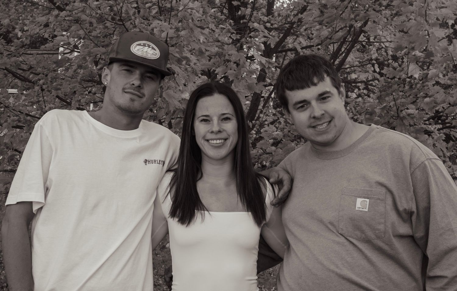 A group of people pose together in a casual black and white portrait shot.
