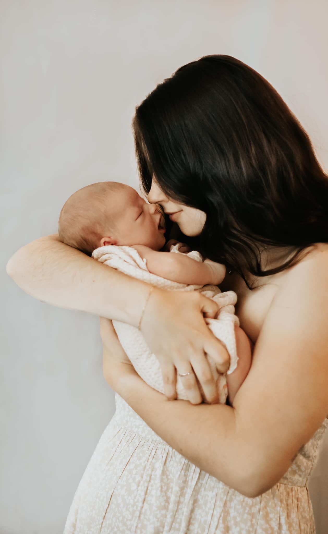 Intimate moments between parent and newborn against a light background.