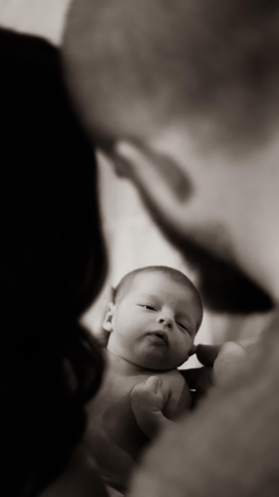 Black and white portrait of a sleeping newborn in soft focus.