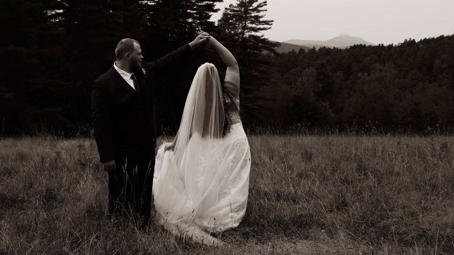 A romantic wedding couple embraces in a golden field during sunset.