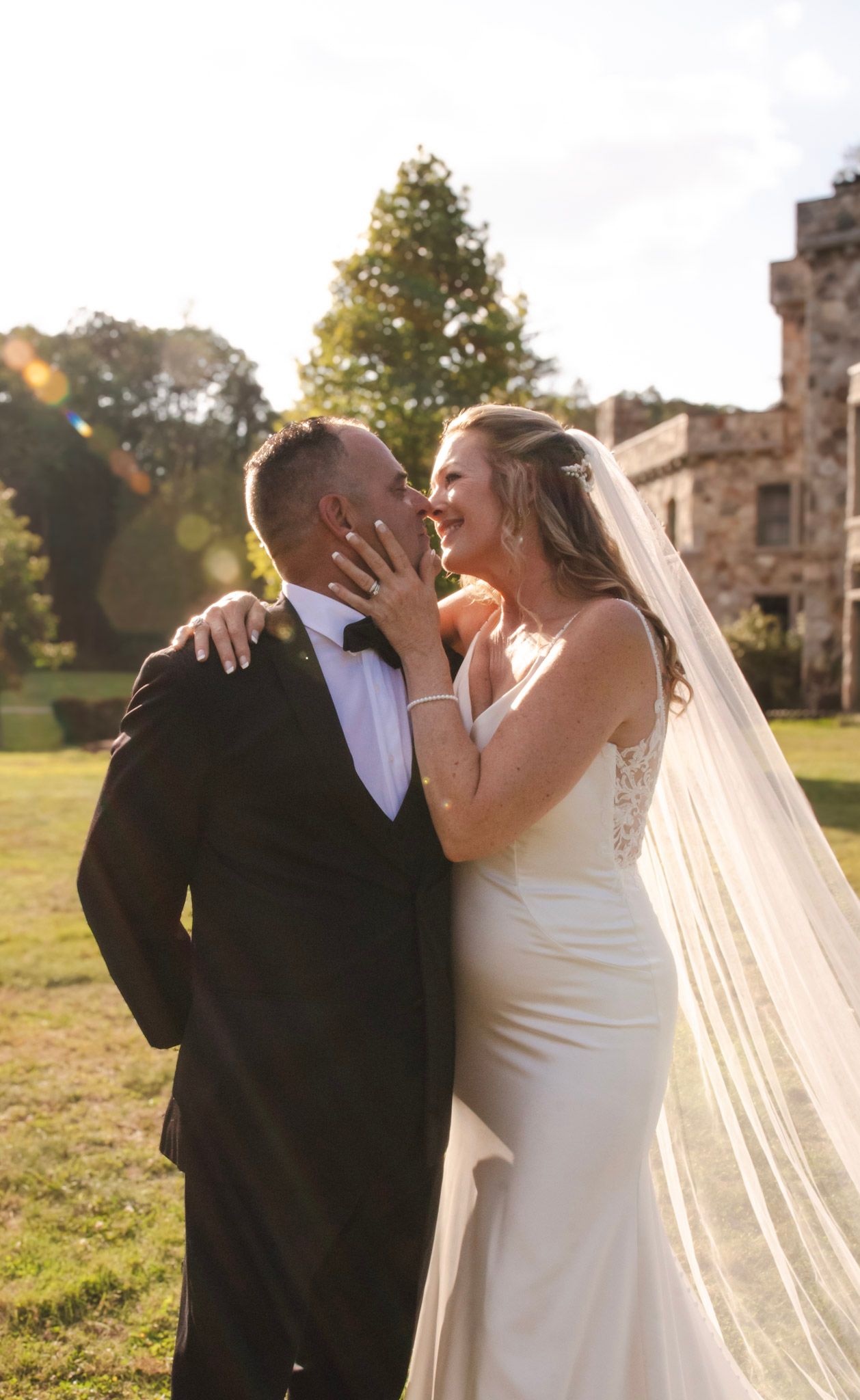 Romantic wedding couple shares intimate kisses in front of stone ruins during golden hour.