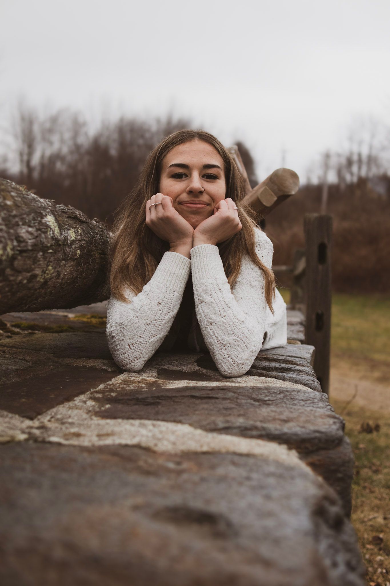A series of three similar photos showing someone in a white sweater leaning on a rustic stone wall outdoors.