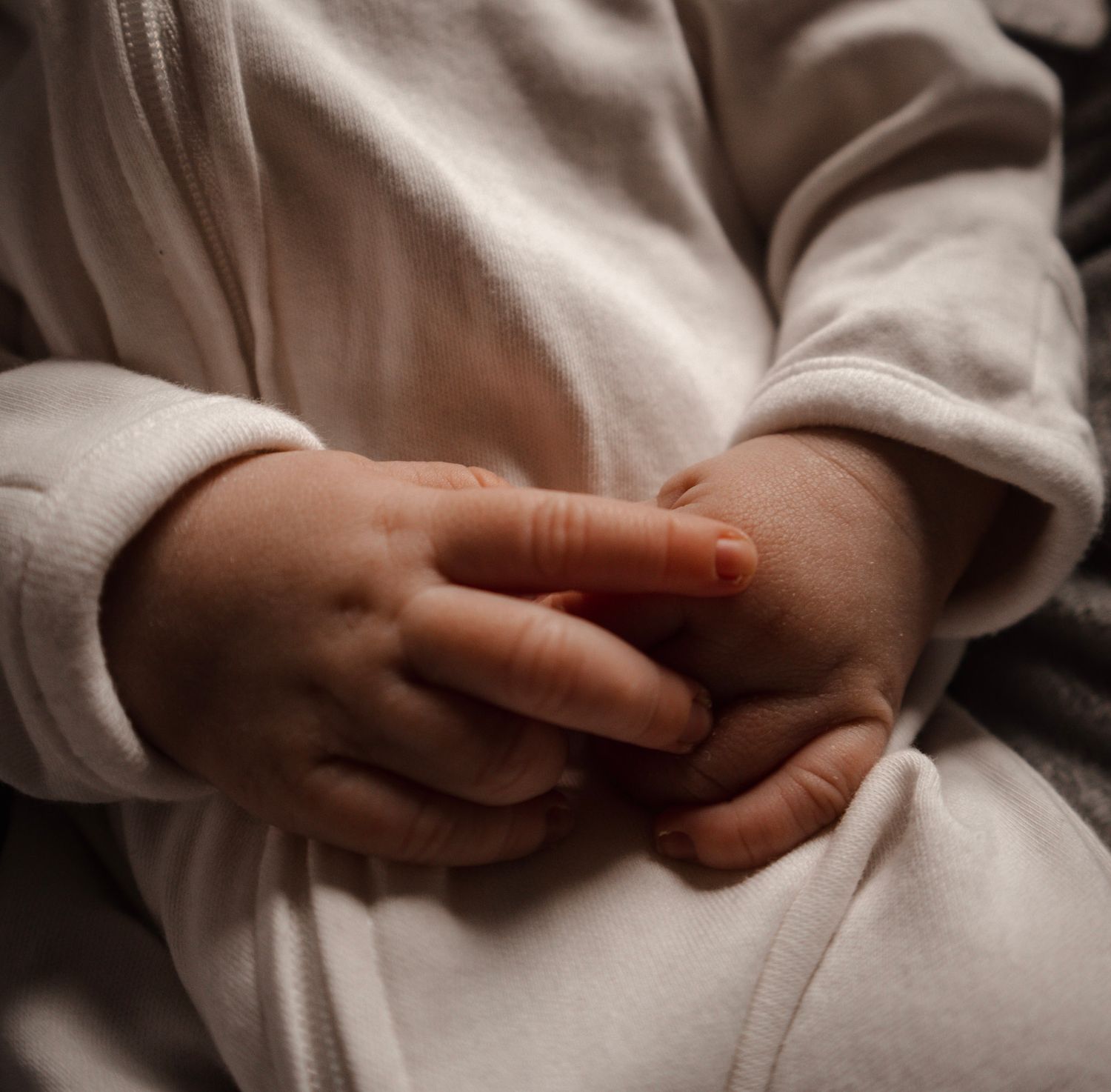 Close-up sequence of hands gently folding white fabric or clothing in a minimalist style.