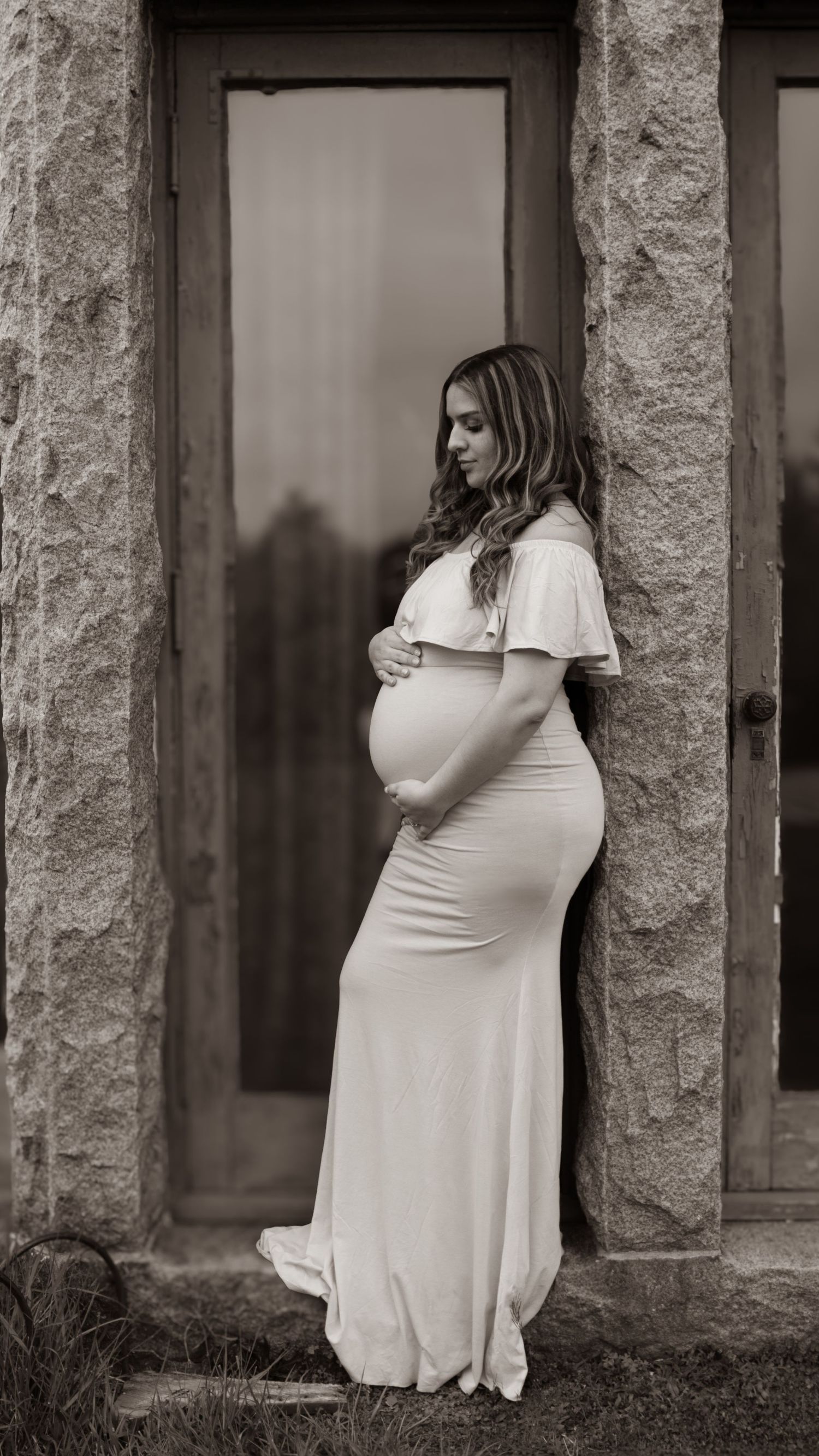 Artistic maternity photos taken against stone columns in black and white.