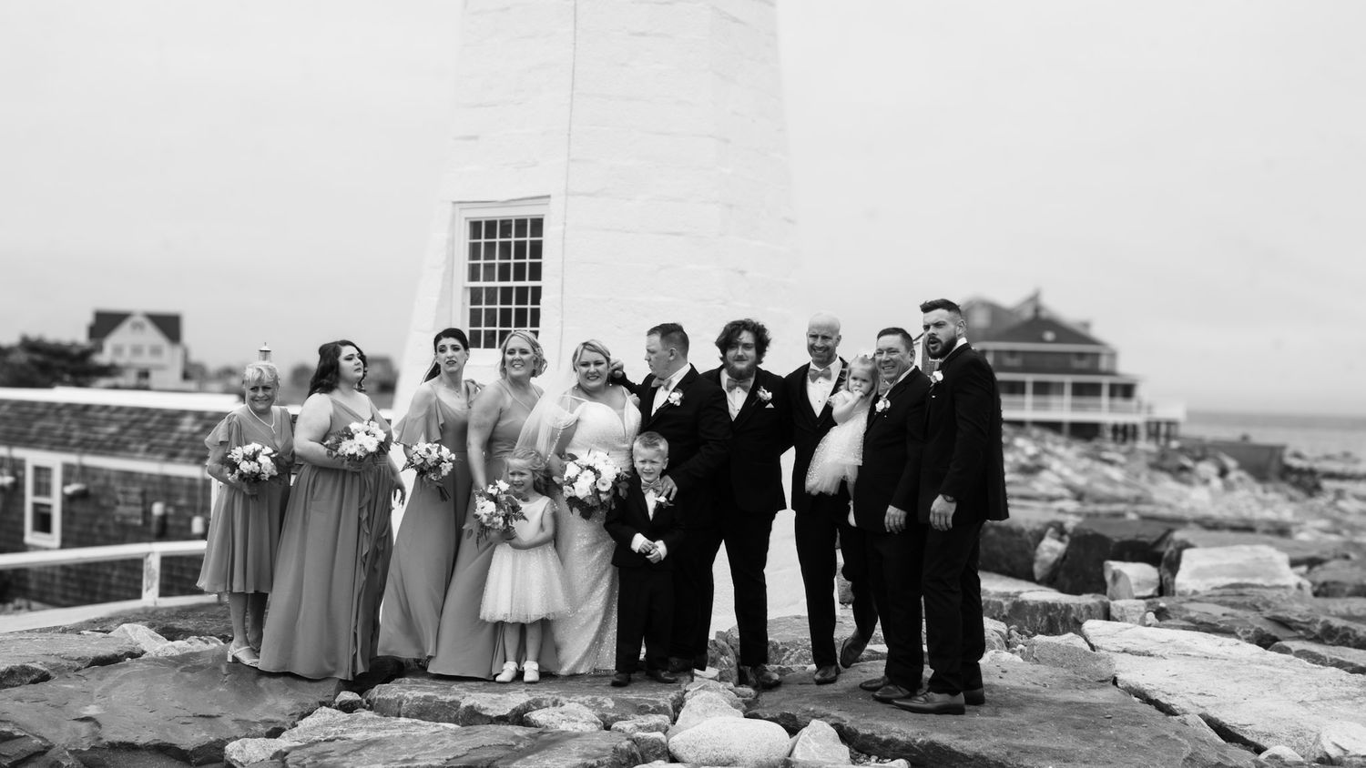 A vintage black and white photograph shows a wedding party posing together on a rooftop in an urban setting.