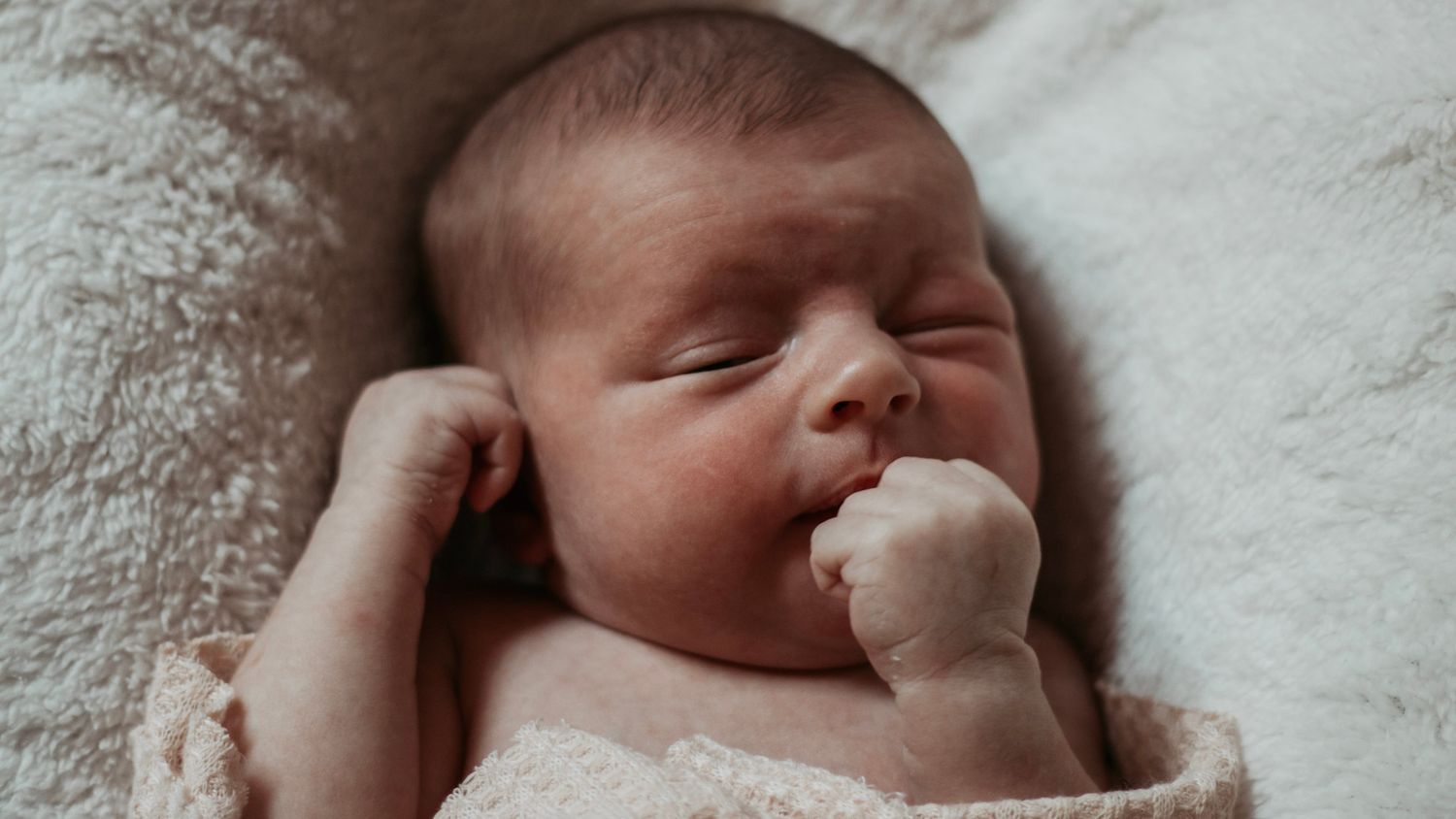 A sleeping newborn baby lying on white bedding in a series of peaceful poses.
