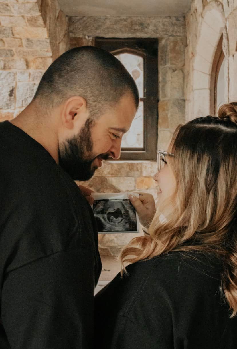 A couple shares an intimate moment against a stone wall background.