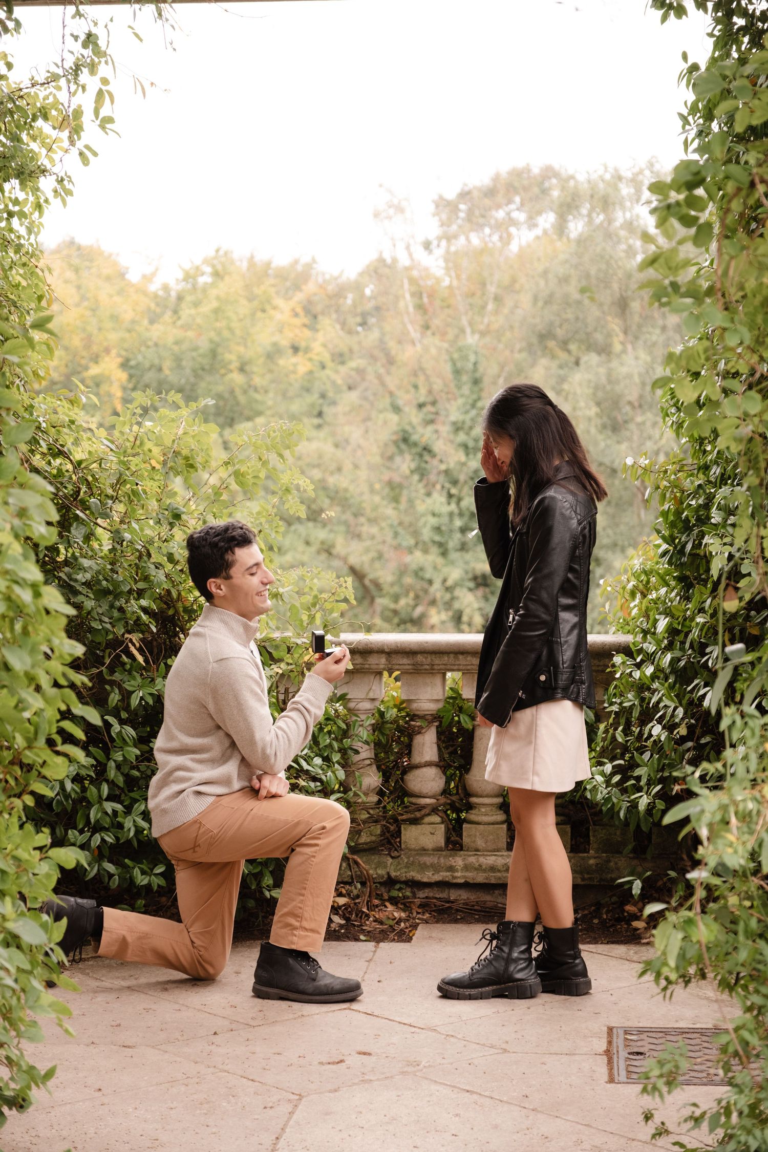 A proposal moment captured in a romantic garden setting surrounded by greenery.