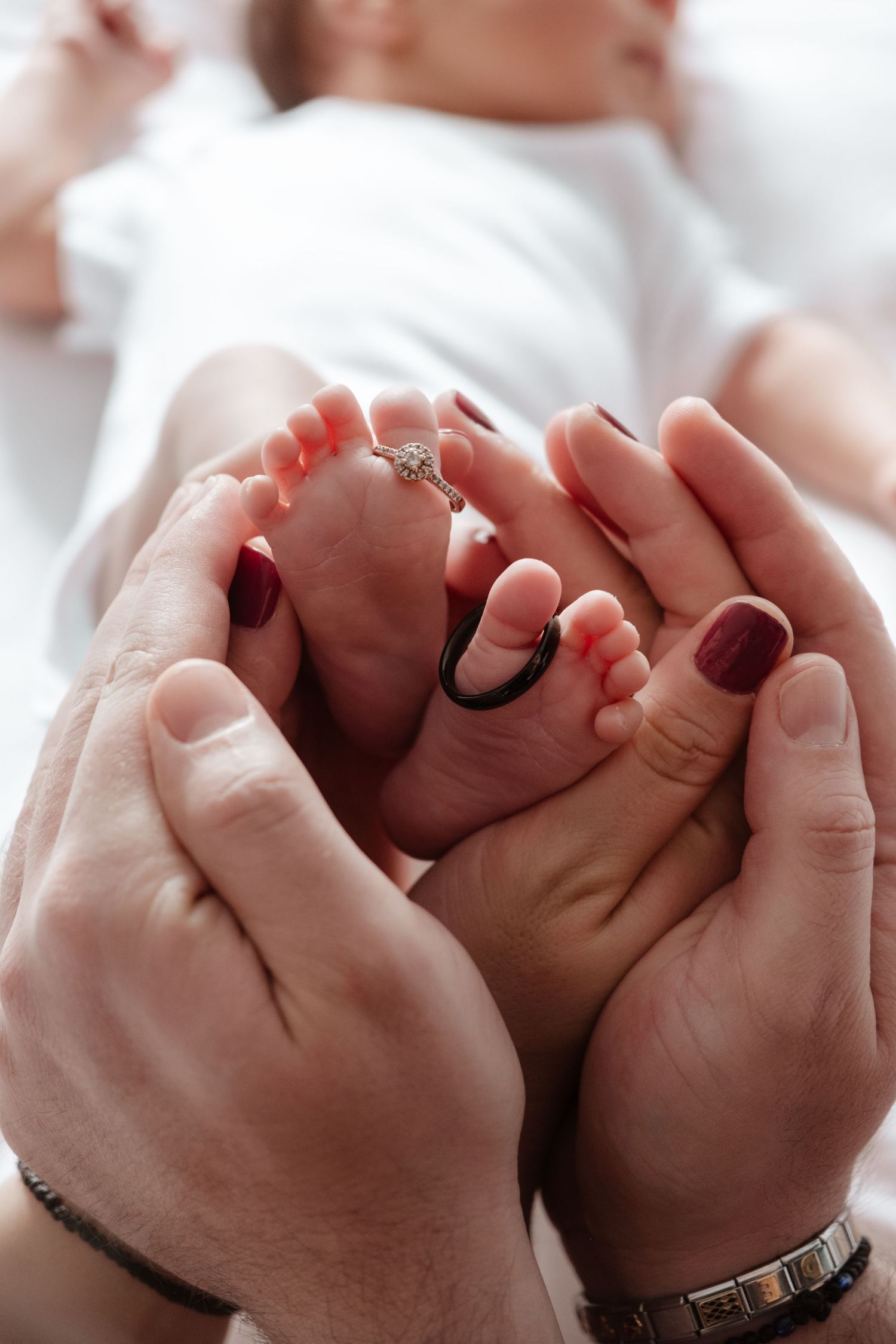 Close-up series of tiny newborn feet being gently held by adult hands.