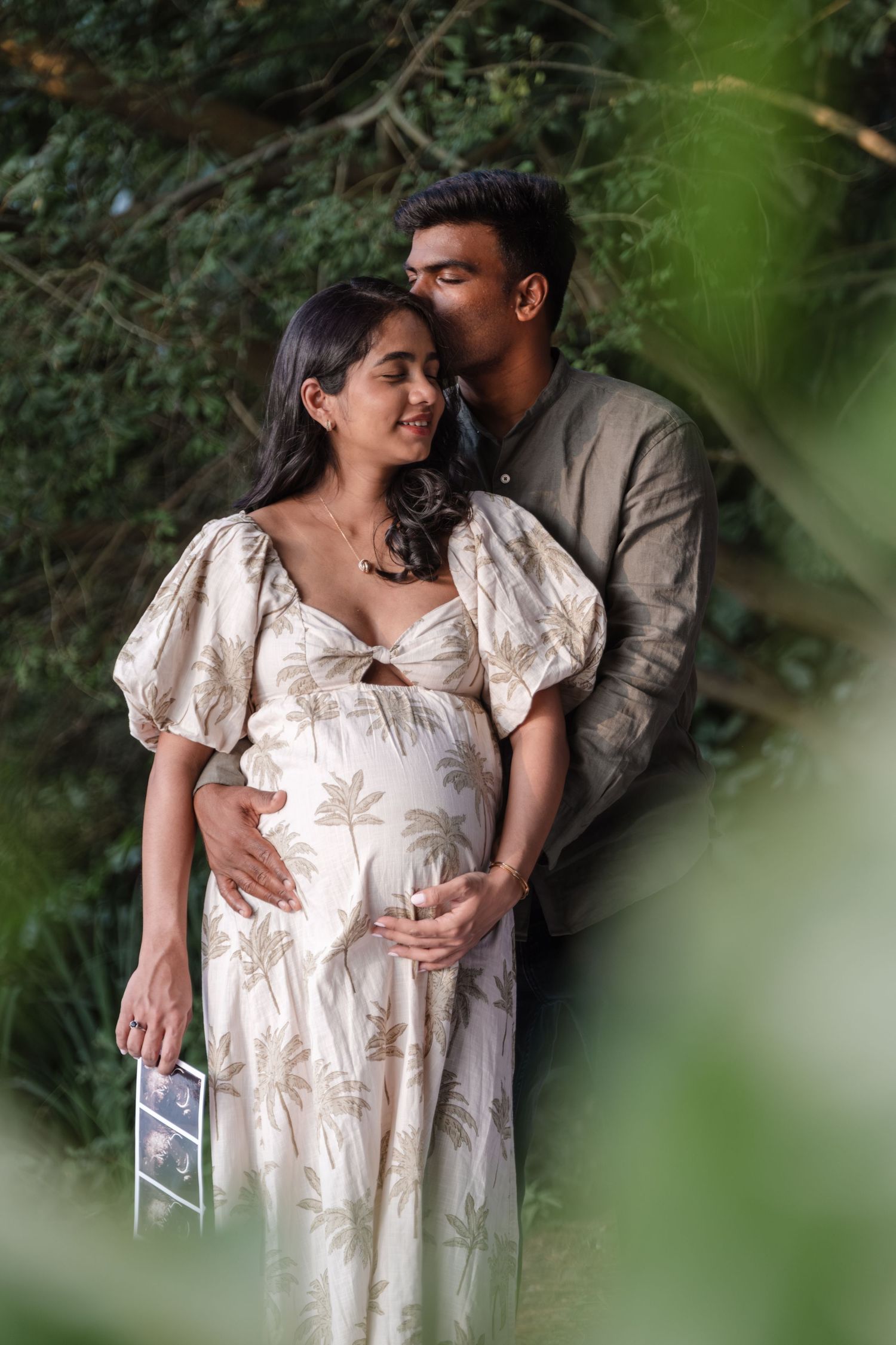 Romantic maternity photo session in garden setting with soft natural lighting.