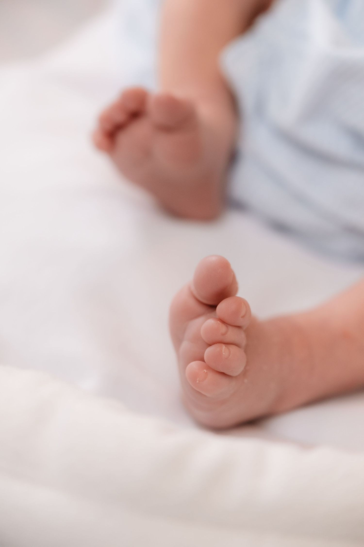 Close-up of tiny baby feet against white bedding.