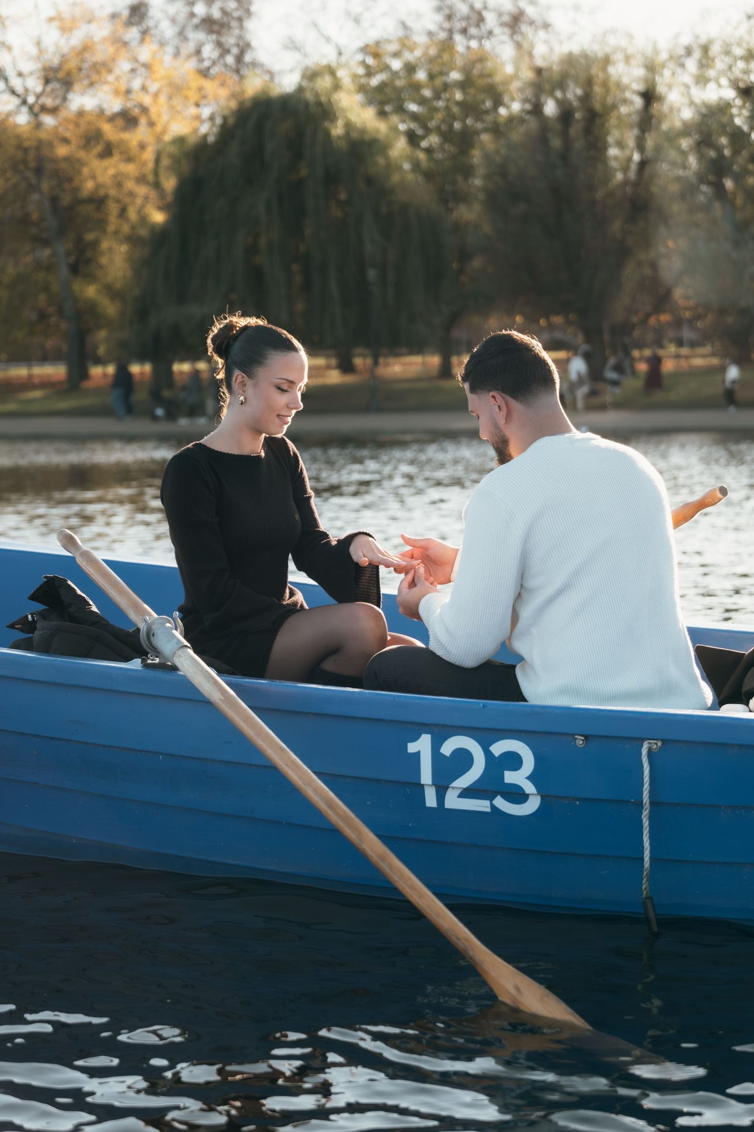 Two people sit in a blue rowboat sharing a special moment on calm waters.