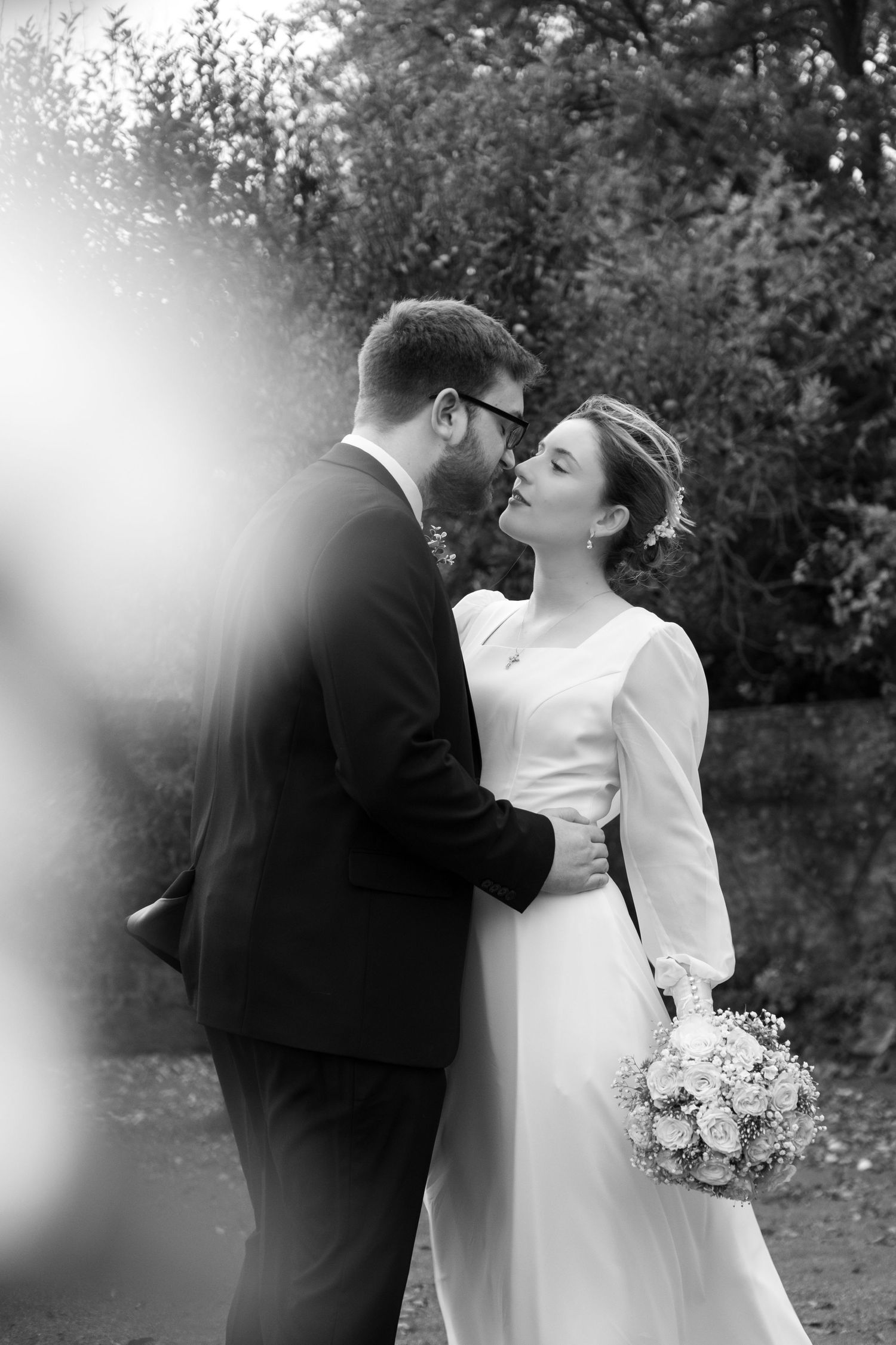 A romantic black and white wedding photo sequence showing a couple embracing outdoors with a bouquet.