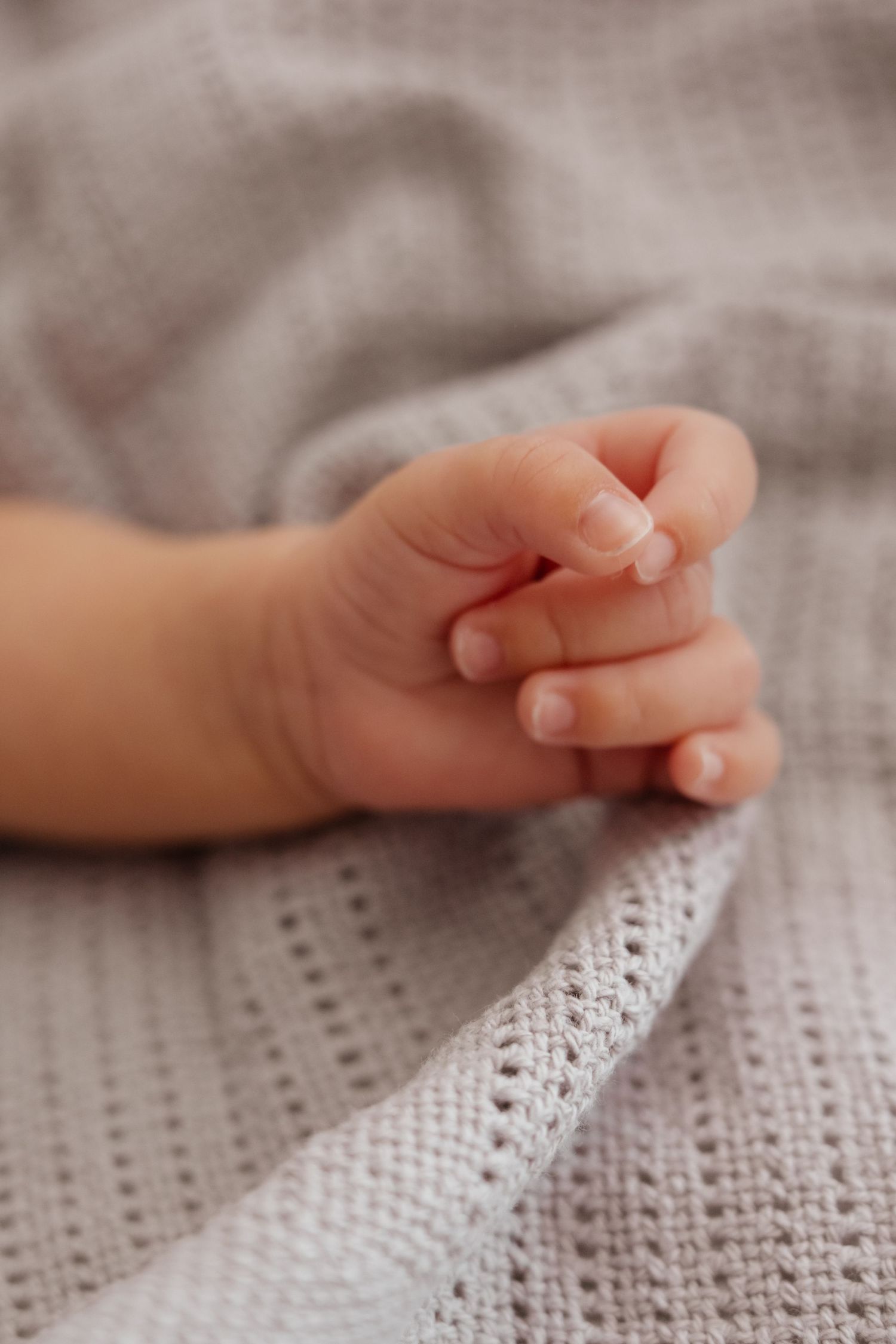 Close-up series of tiny baby hands resting on textured white fabric.