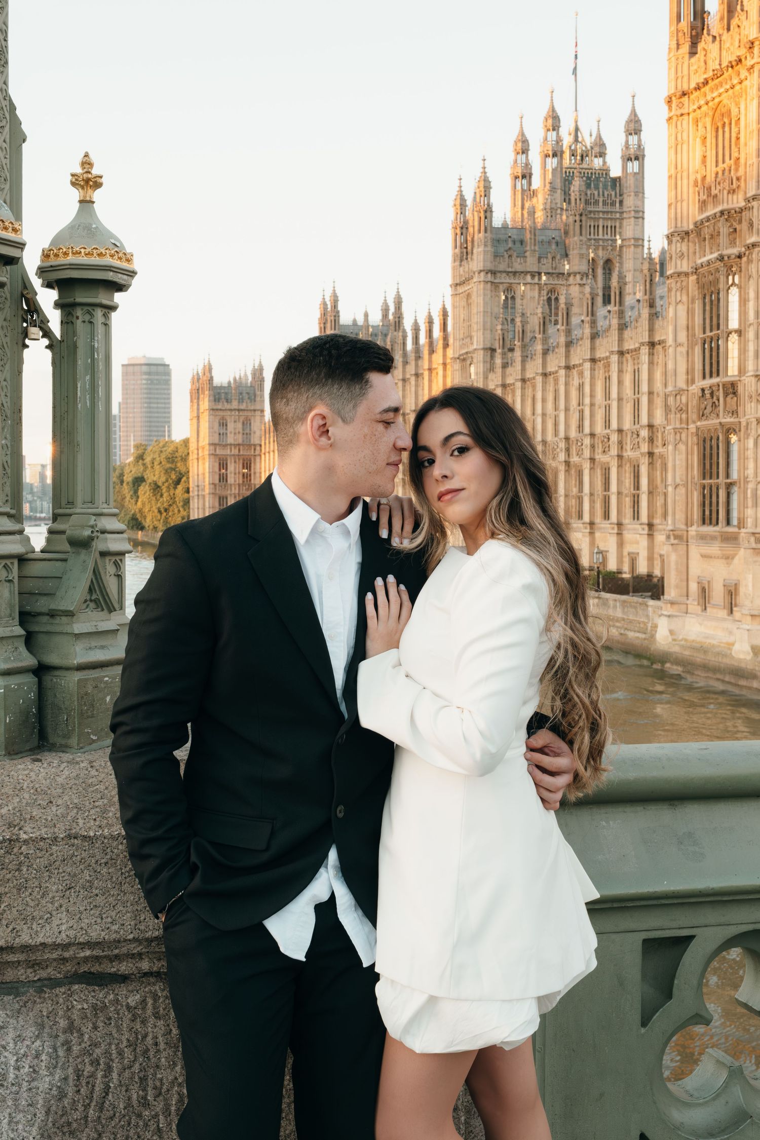A couple poses romantically in front of the Houses of Parliament in London.