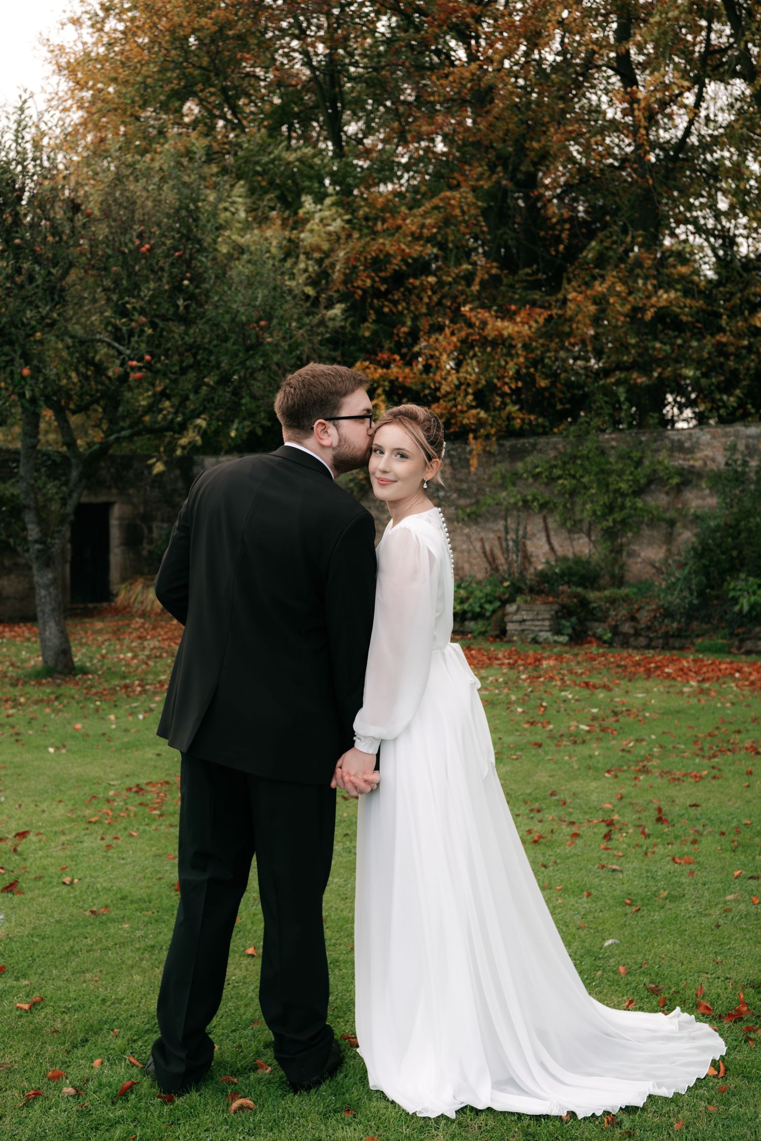 Autumn wedding photoshoot sequence with couple on grass with fallen leaves.