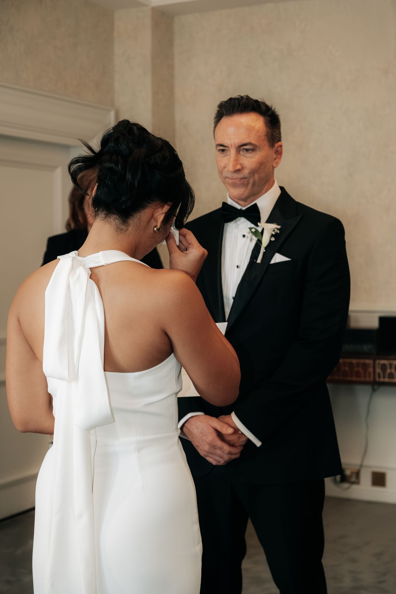 Elegant wedding couple sharing an intimate moment in formal attire at an indoor venue.