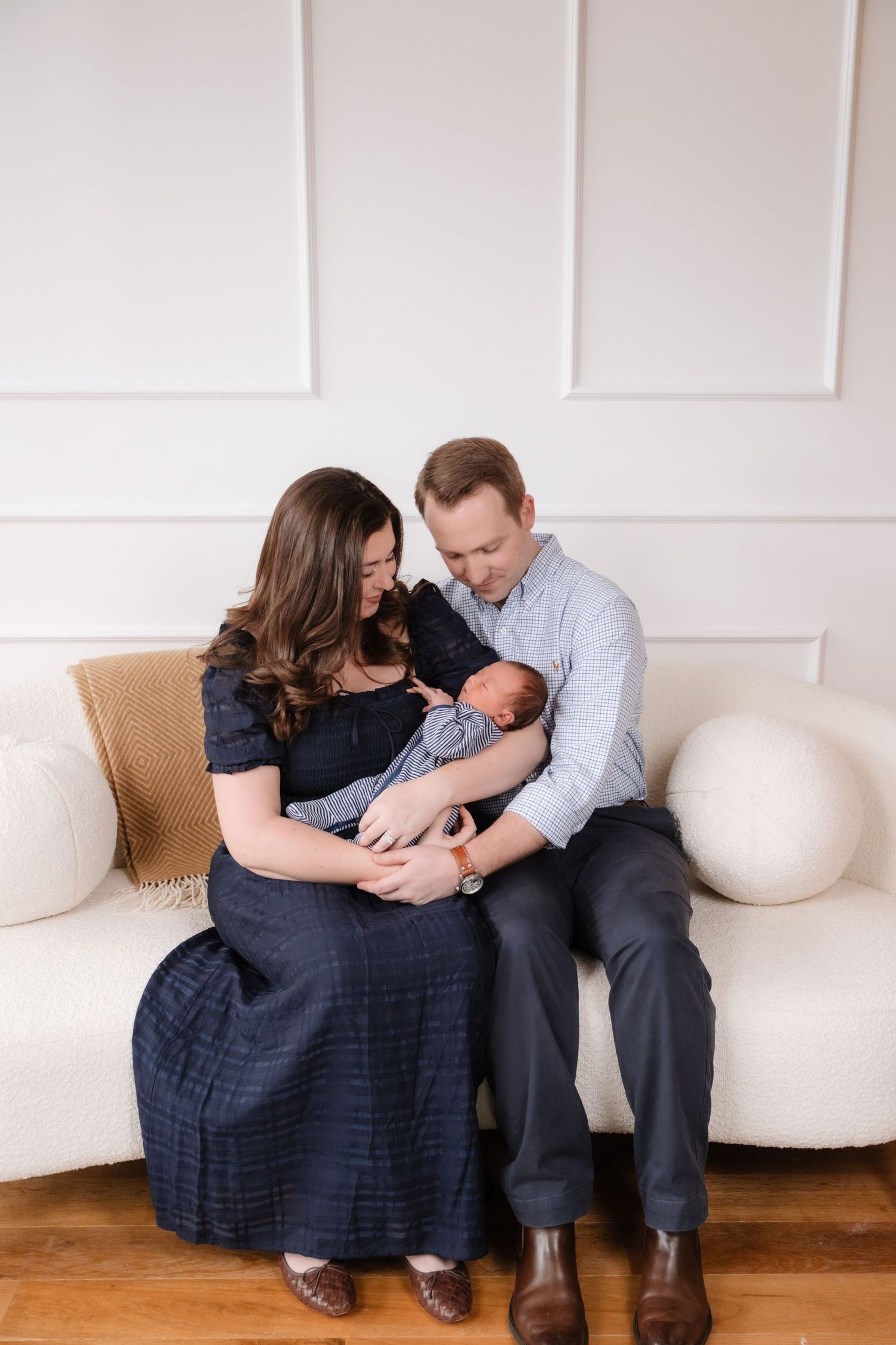 Intimate family moment on a white couch with a newborn baby.