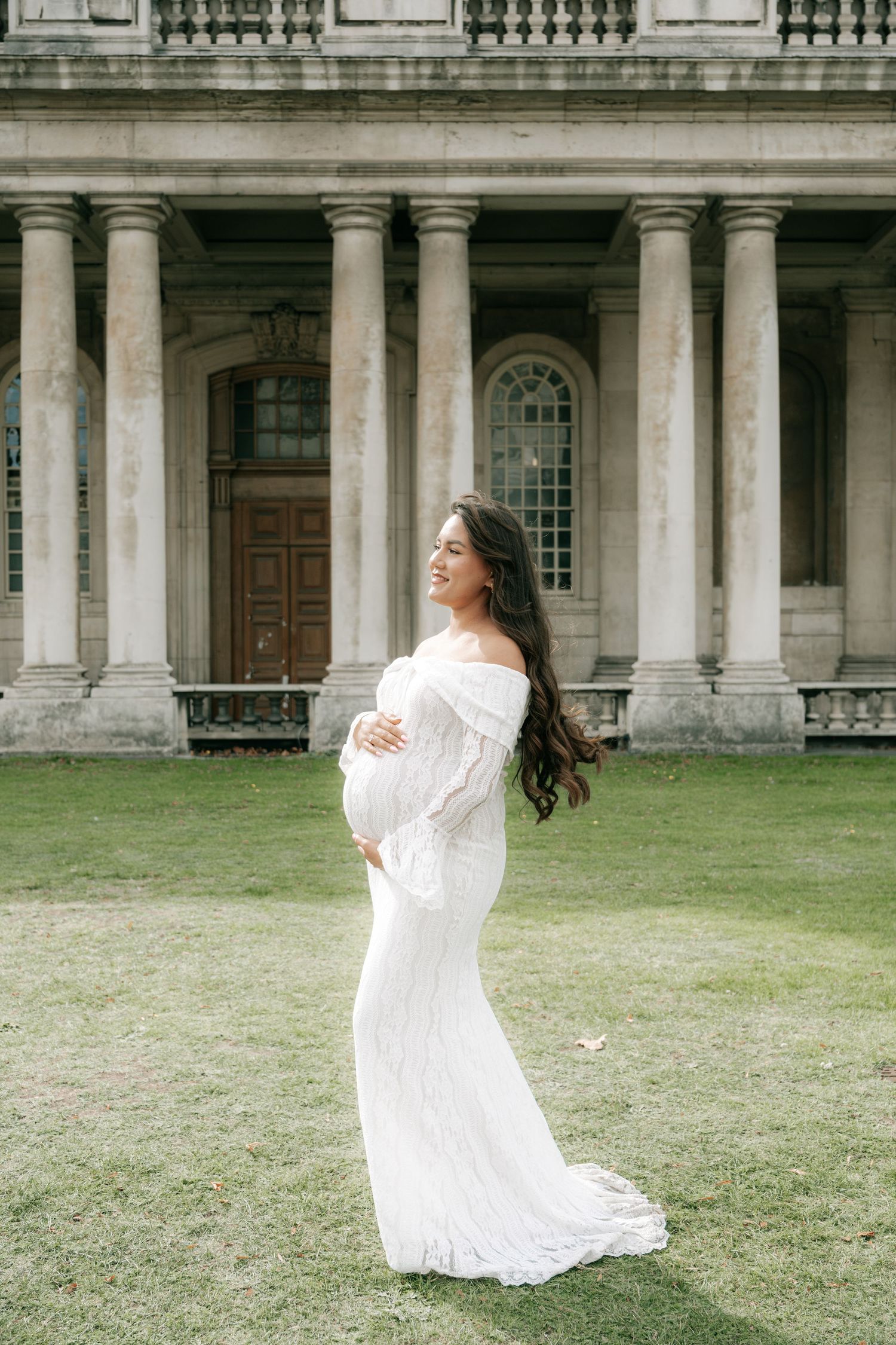 A figure in a flowing white dress twirls gracefully against the backdrop of a historic stone building.