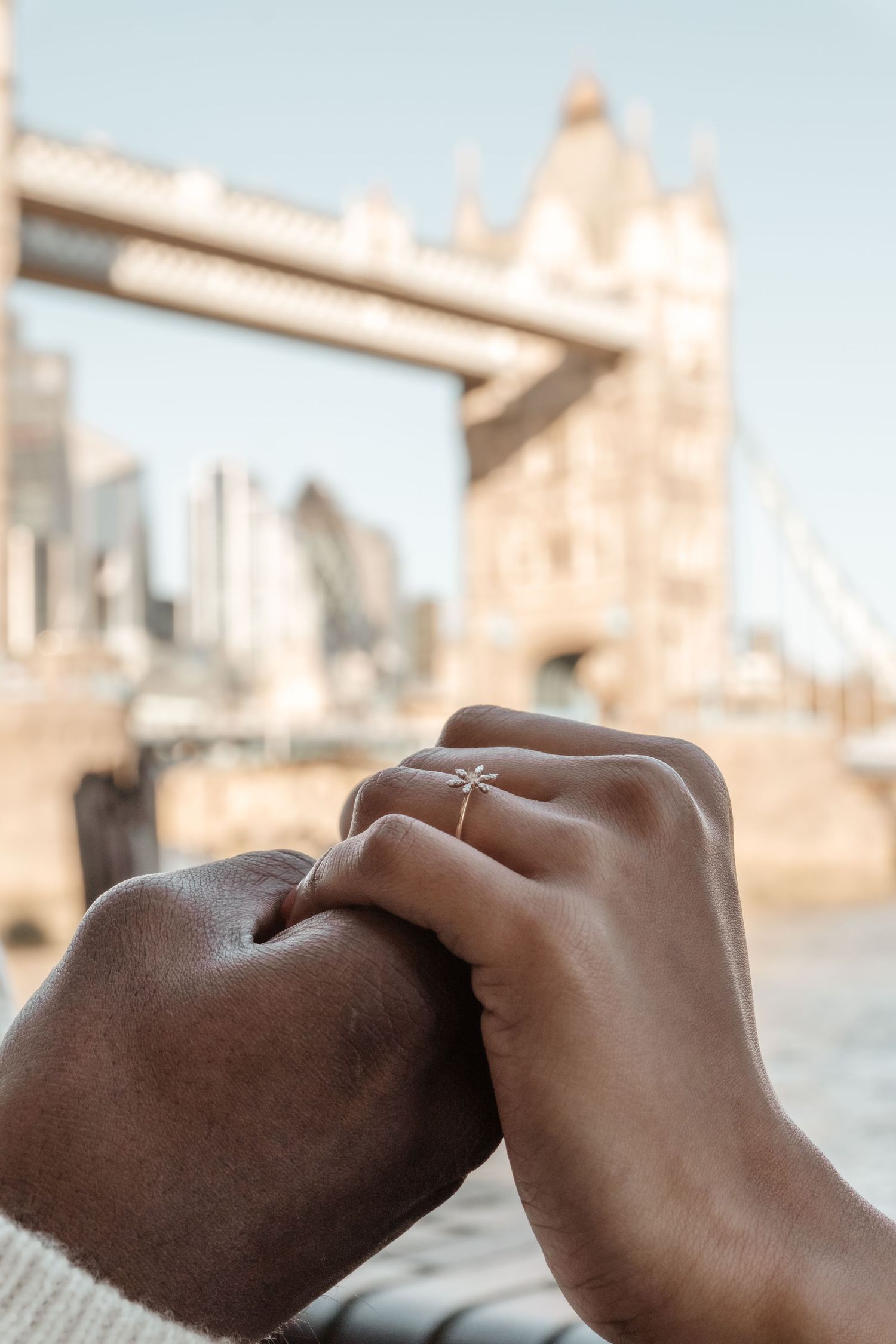 Close-up sequence of hands touching tenderly with Tower Bridge visible in the background.