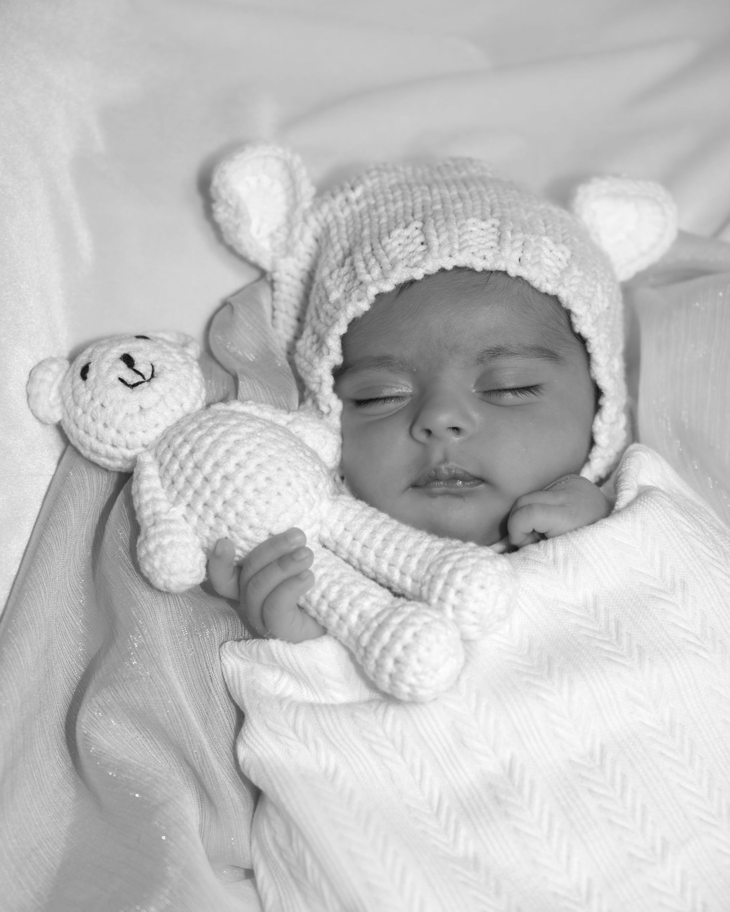 Series of peaceful sleeping newborn photos with white knitted bear hat against white background.