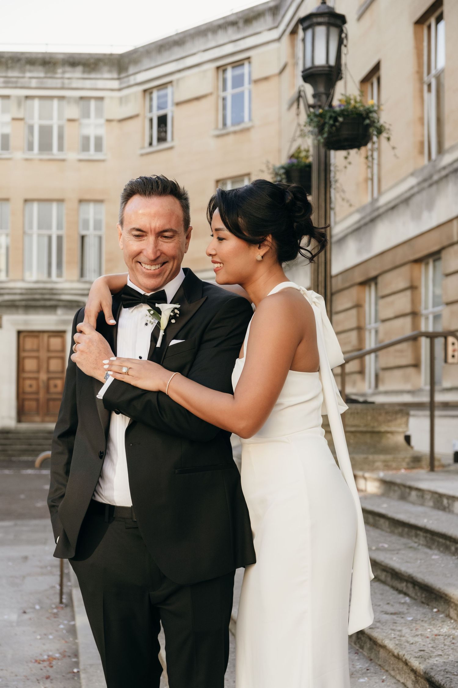 Happy couple sharing joyful moment outside historic building during wedding celebration.