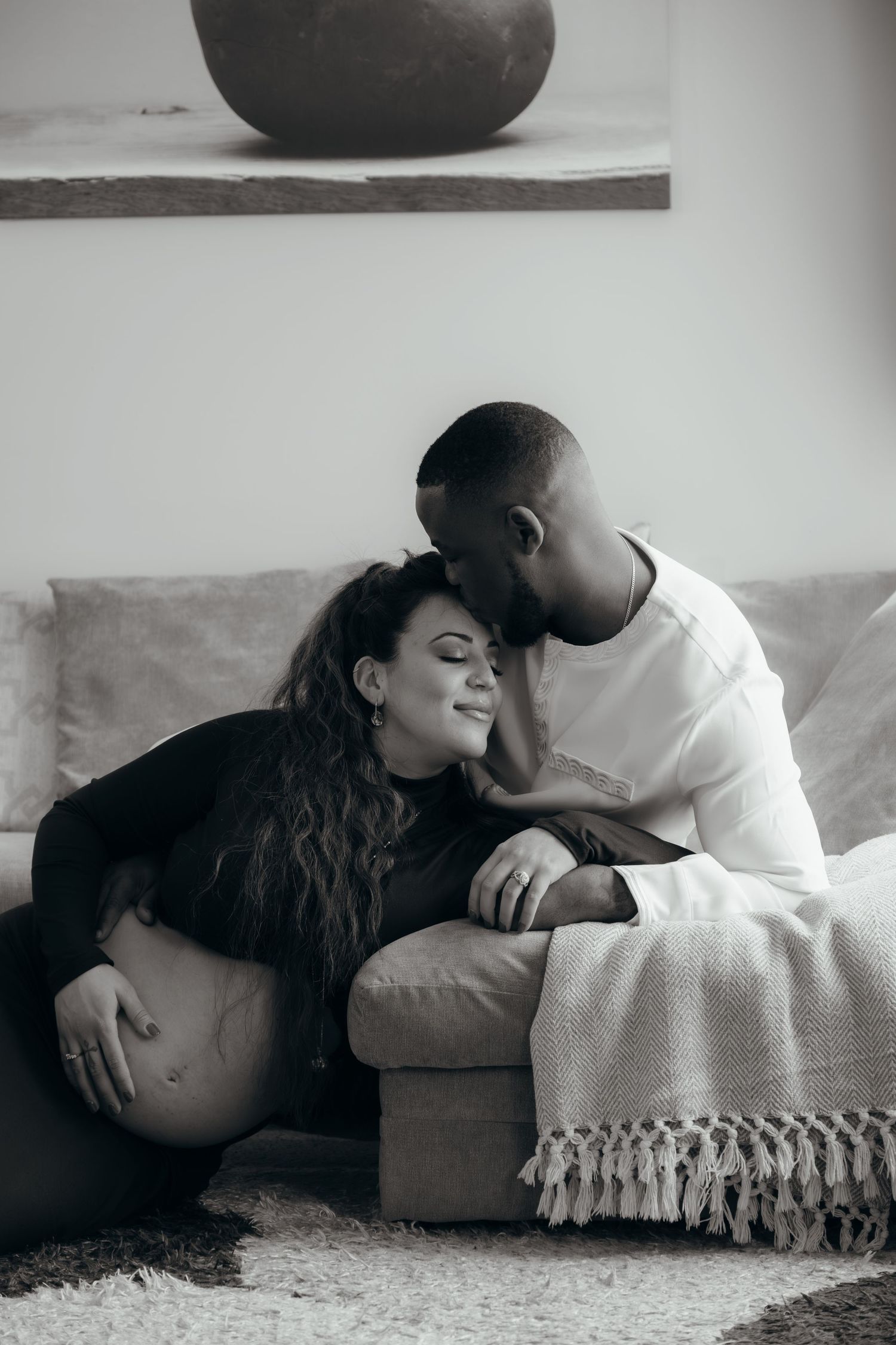 Black and white photo series showing a tender moment between a couple lying on the floor with a blanket.