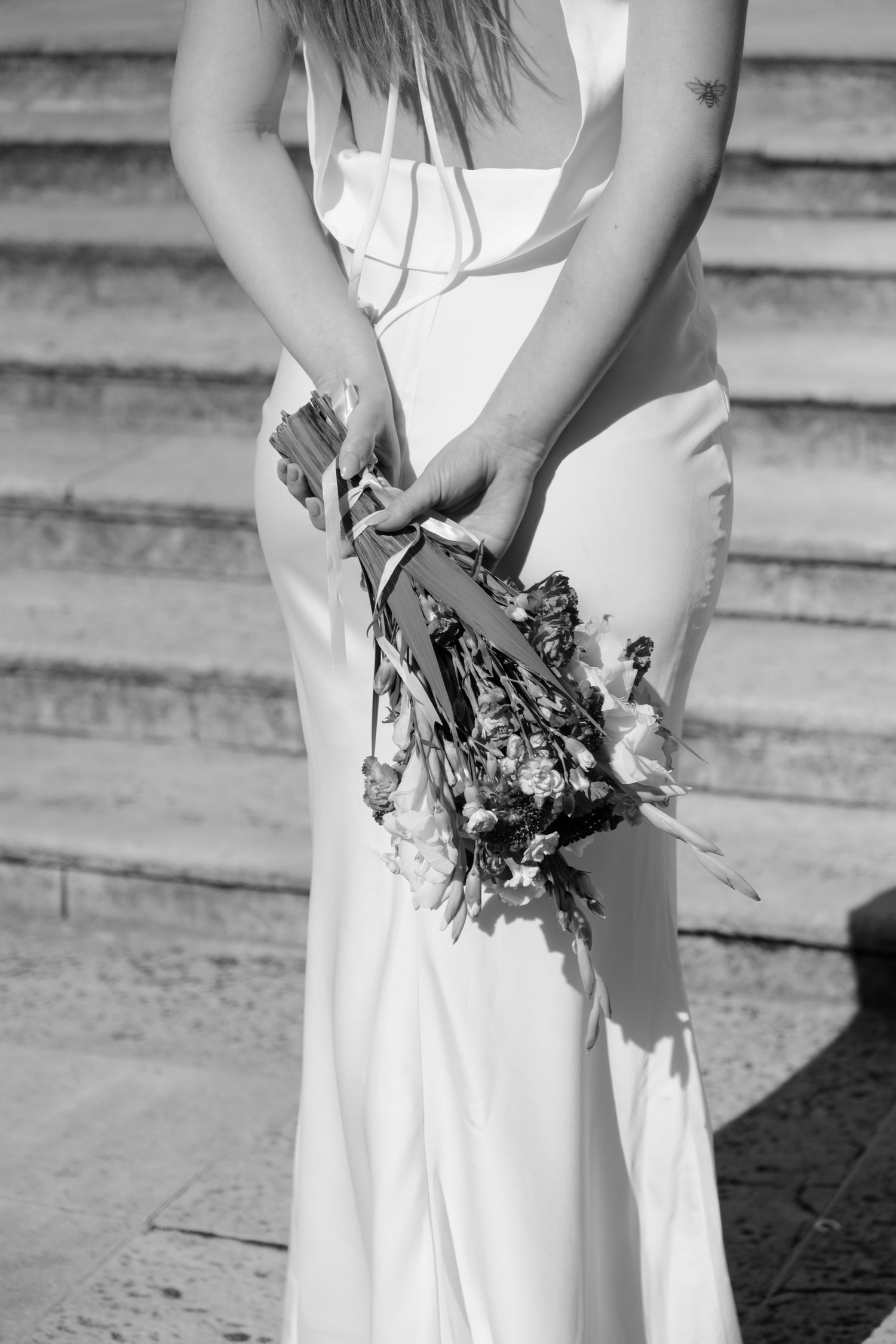 Black and white detail shots of bride holding wedding bouquet on stone steps.