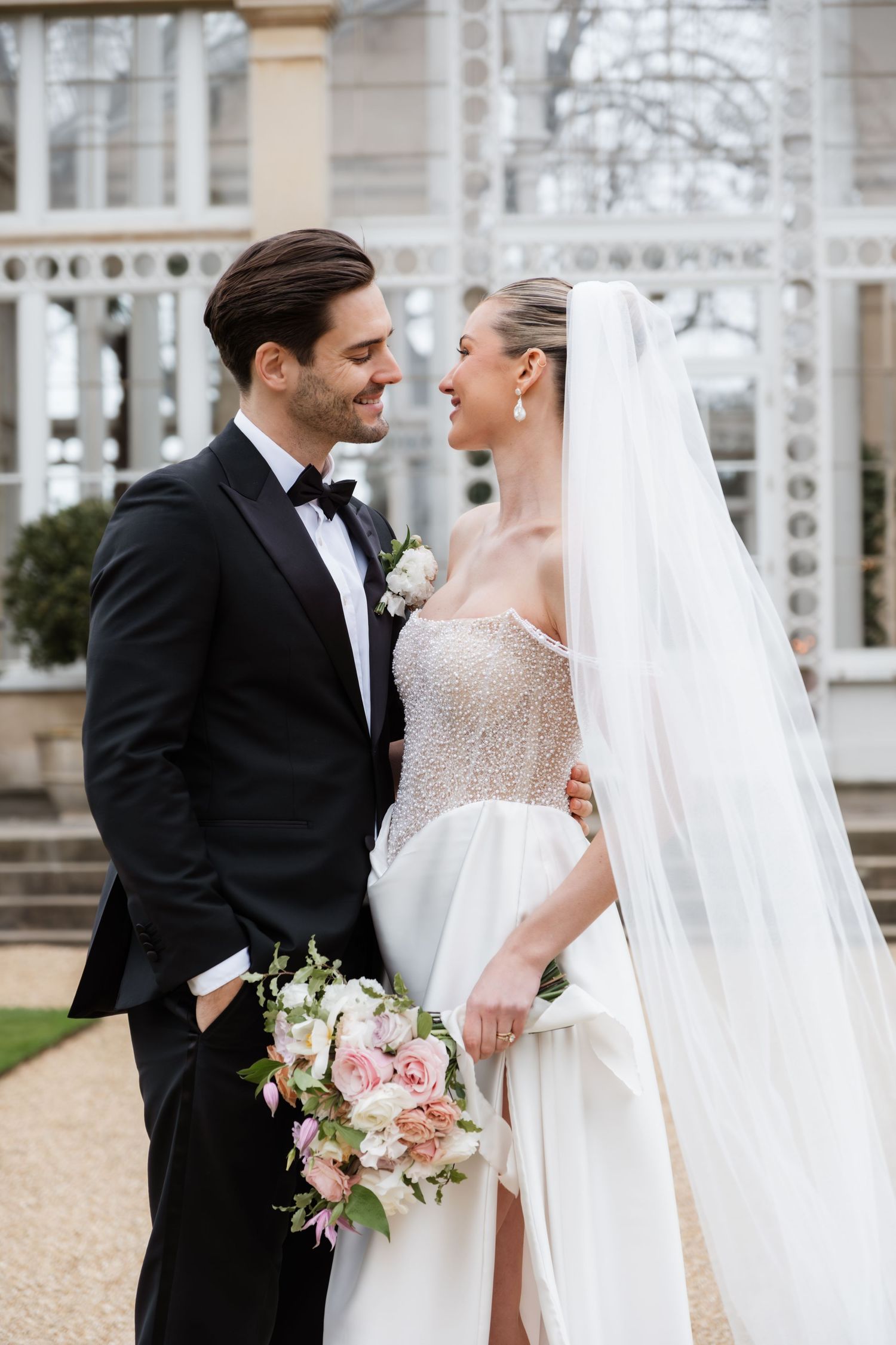 Elegant wedding couple sharing intimate moments in a sunlit conservatory.