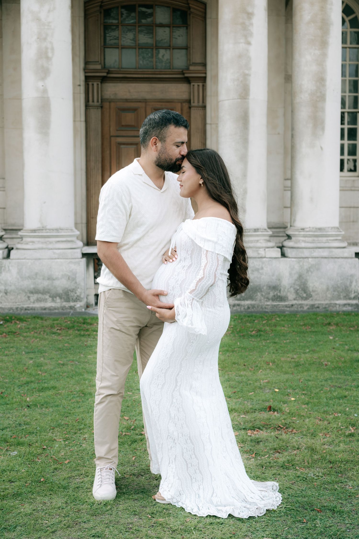 Romantic moment captured on lawn in front of historic columned architecture.