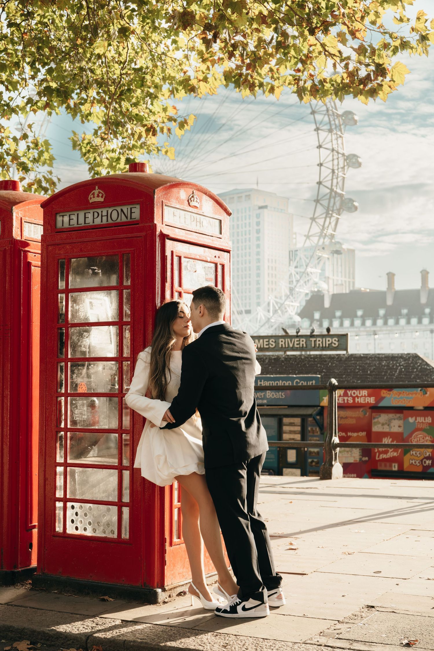 A couple poses playfully by classic red British telephone booths in London.