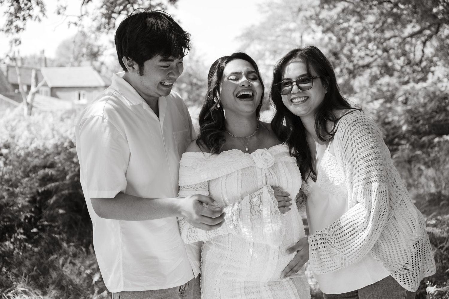 Joyful outdoor maternity photography session with couple in white outfits.