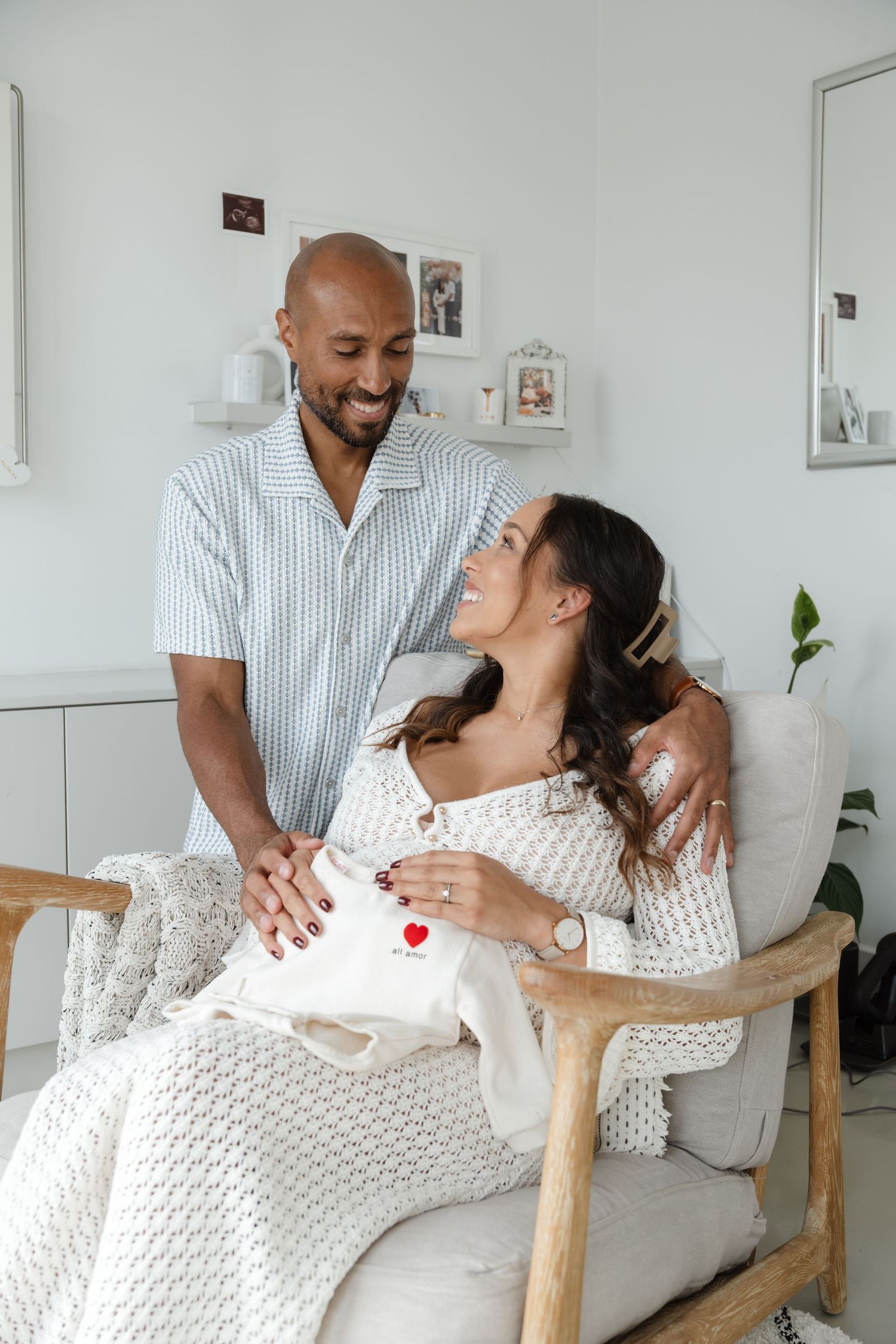 Couple relaxes in a bright room with wooden furniture during an intimate photoshoot.