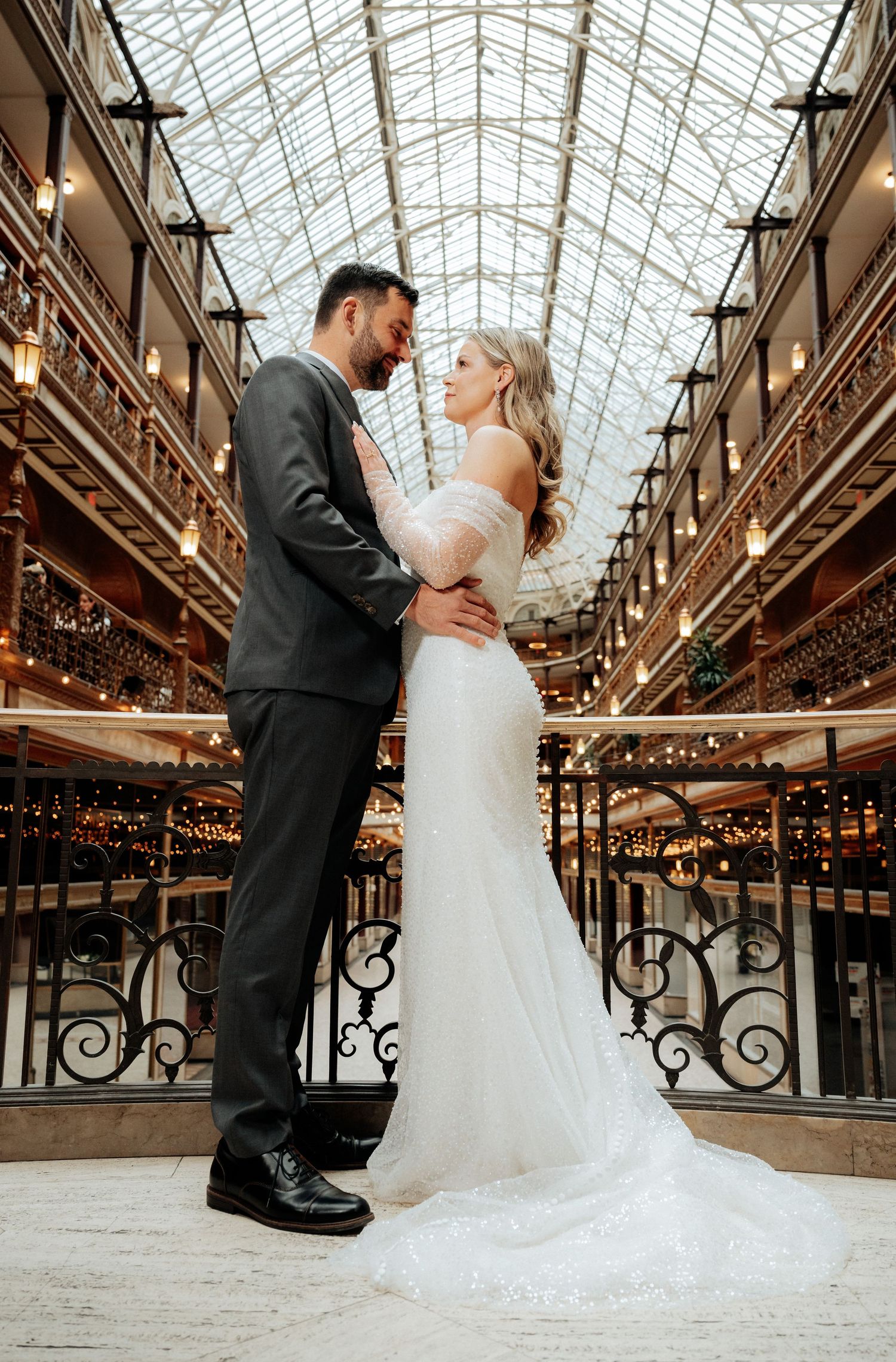 A romantic wedding couple shares an intimate moment in the historic Cleveland, Ohio arcade with ornate railings and glass ceiling.
