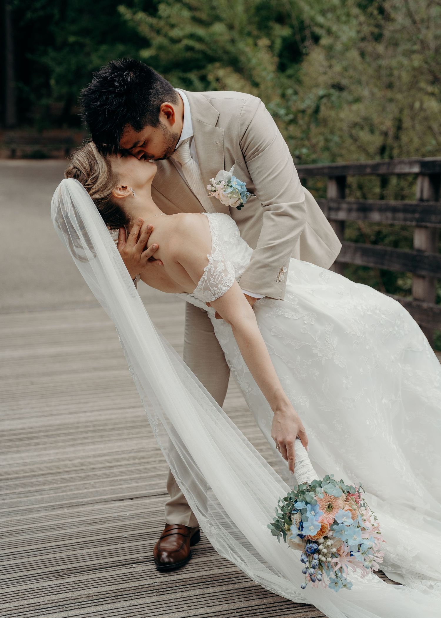 Bruidspaar deelt romantisch moment op houten terras met witte jurk en blauwe bloemdetails – bruidsfotografie, trouwdag, Nederland