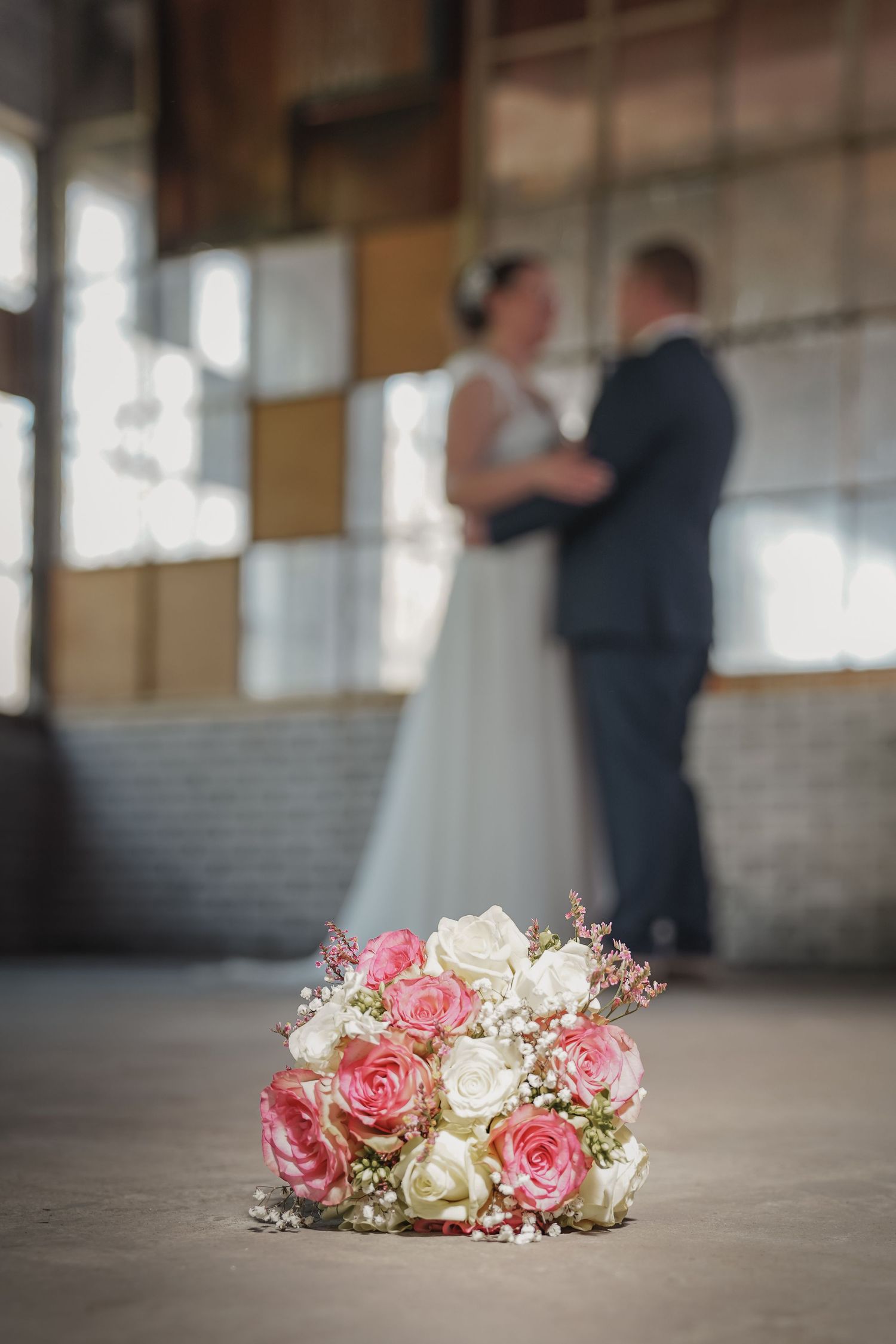 Romantisch bloemenarrangement van roze en witte rozen met wazig bruidspaar op achtergrond – bruidsfotografie, trouwdag, Nederland