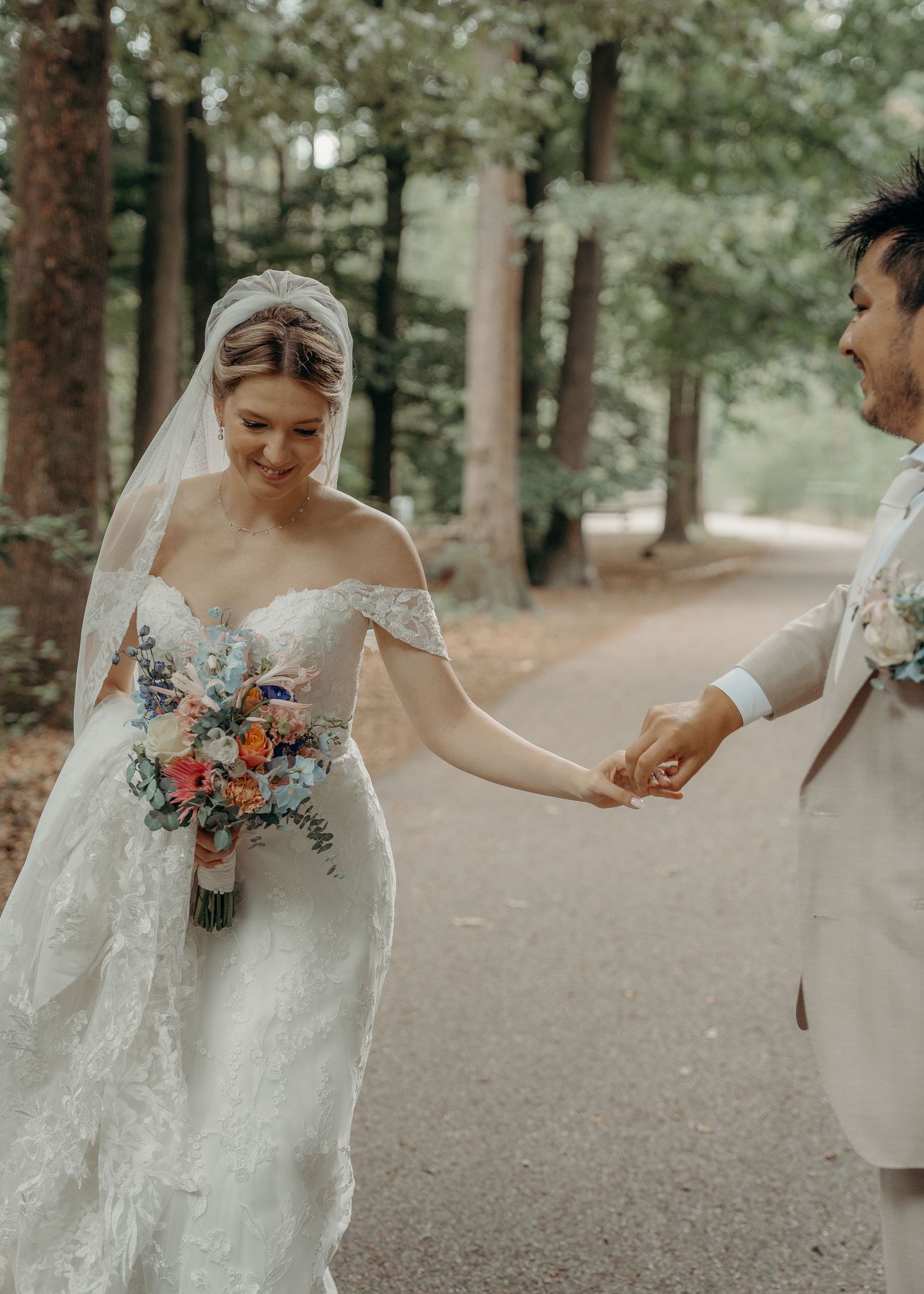 Bruid in kanten jurk met kleurrijk bruidsboeket wandelt over bospaadje – bruidsfotografie, trouwdag, Nederland